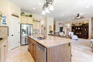 Spacious kitchen with a large island featuring dual sinks, granite countertops, tile flooring, and integrated stainless steel appliances