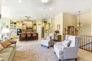 Spacious living area featuring high ceilings, light-toned walls, and a wrought iron staircase railing