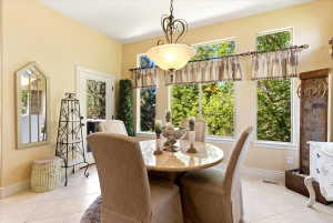 Dining area featuring a central chandelier, multiple large windows, tile flooring, a glass-paned exterior door, and detailed baseboards