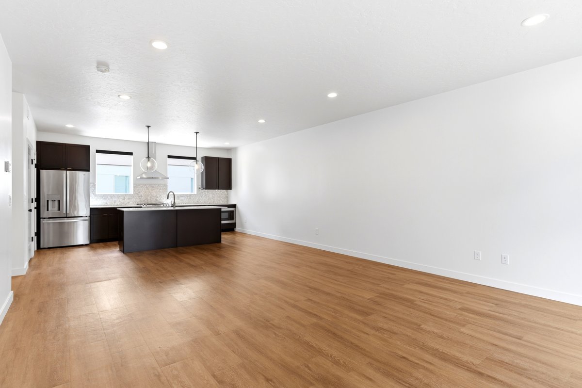 Open-concept living area featuring wood-finish flooring, recessed lighting, and a modern kitchen