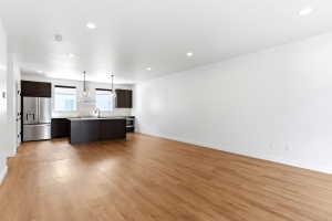 Open-concept living area featuring wood-finish flooring, recessed lighting, and a modern kitchen