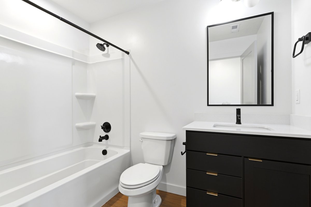 Bathroom featuring a black vanity with gold-tone hardware, white countertop, and integrated sink
