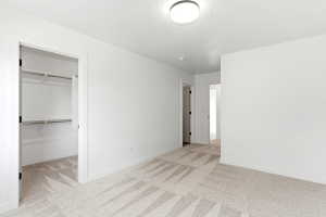 Spacious room featuring light-toned patterned carpet and crisp white walls