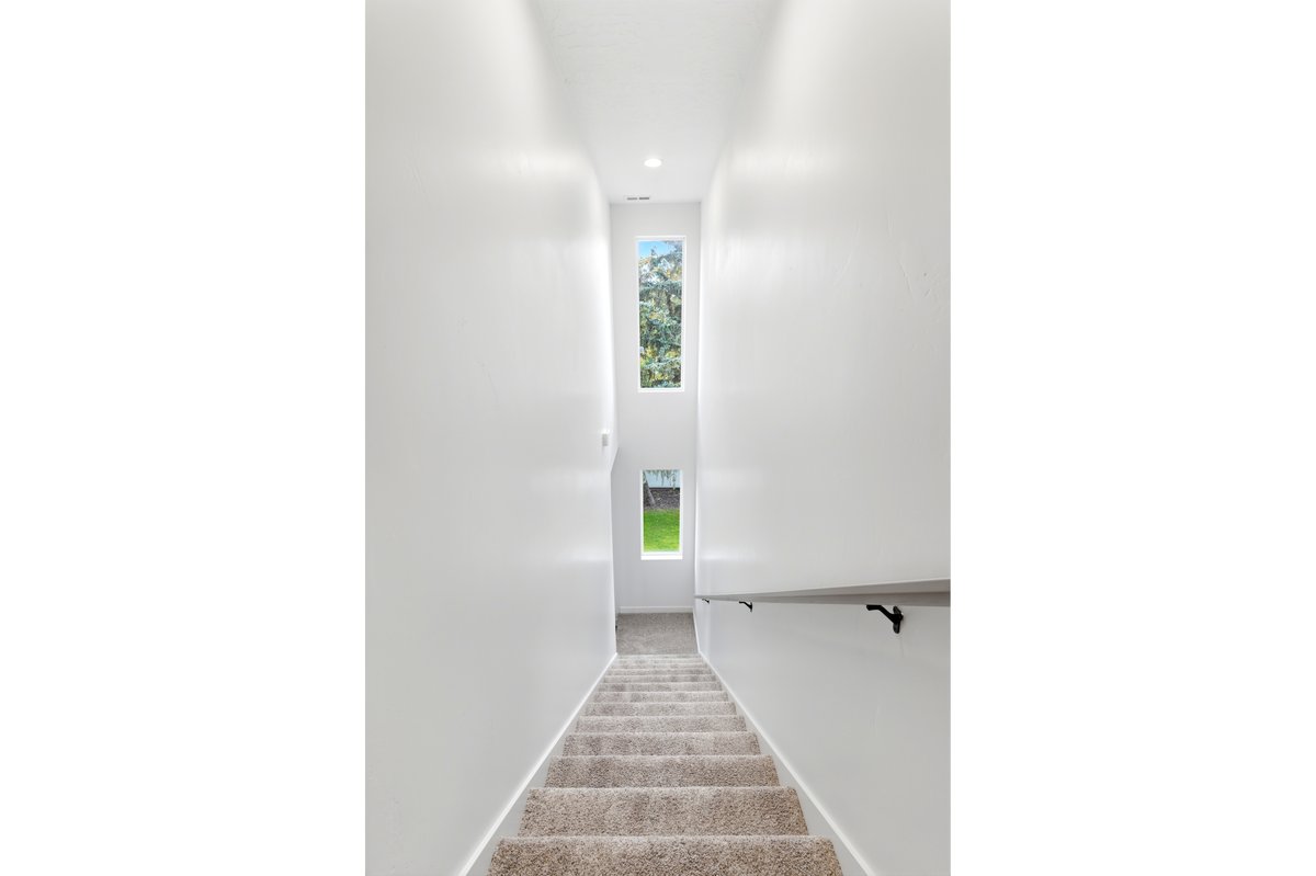 Staircase with carpeted treads and a light-colored railing