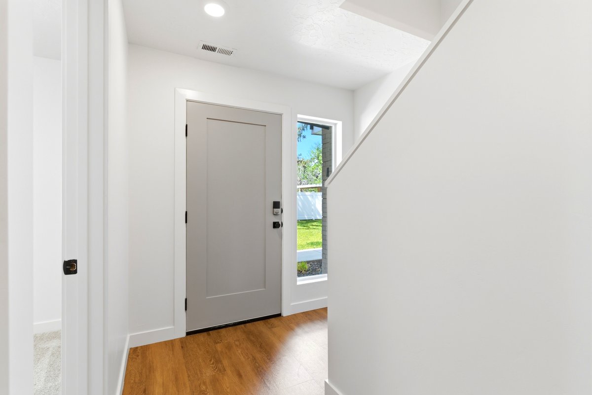Entryway featuring wood-finish flooring, a contemporary light gray door with black hardware, and an adjacent sidelight window
