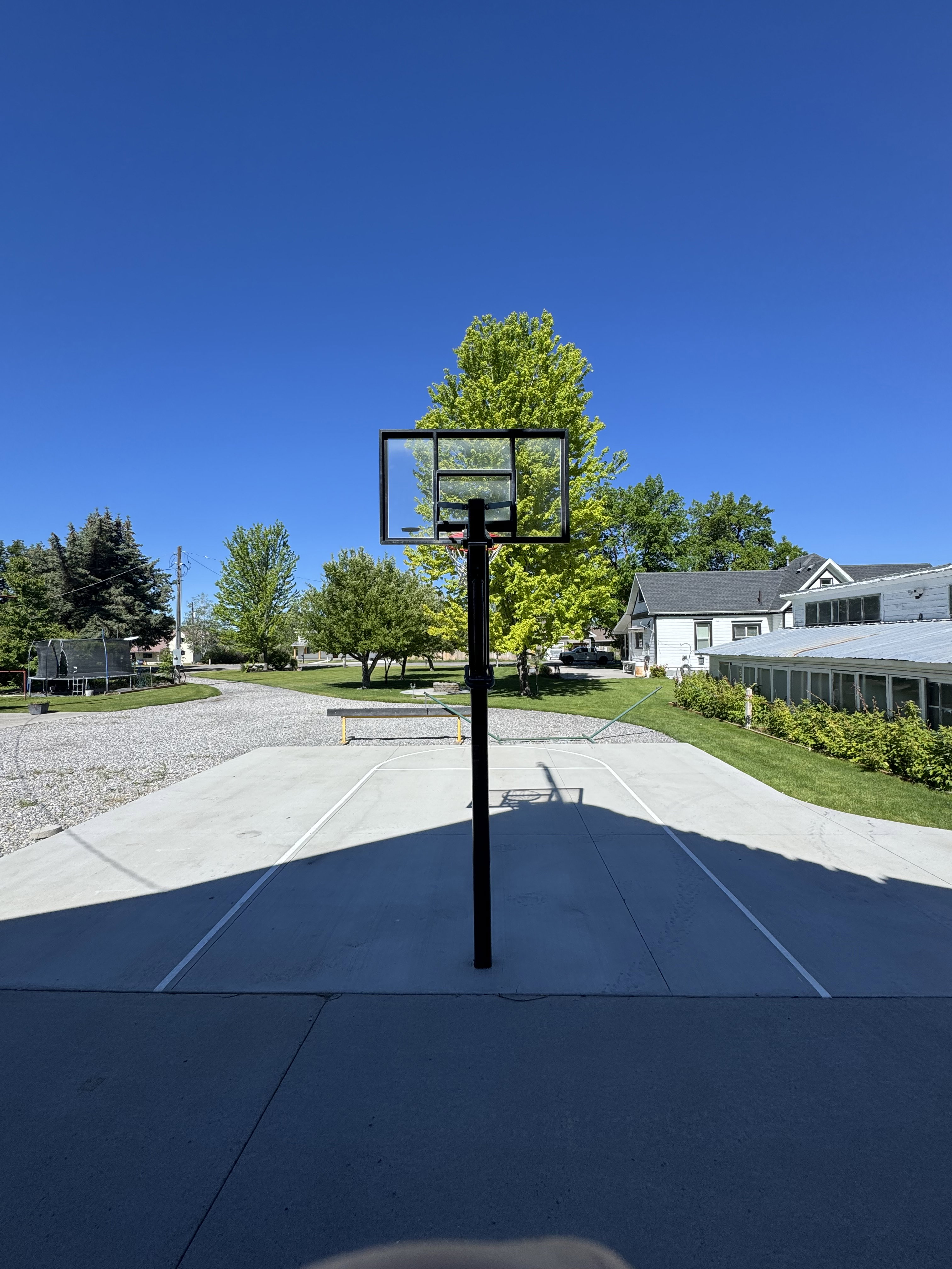 Concrete half-court basketball area featuring a clear backboard and black pole