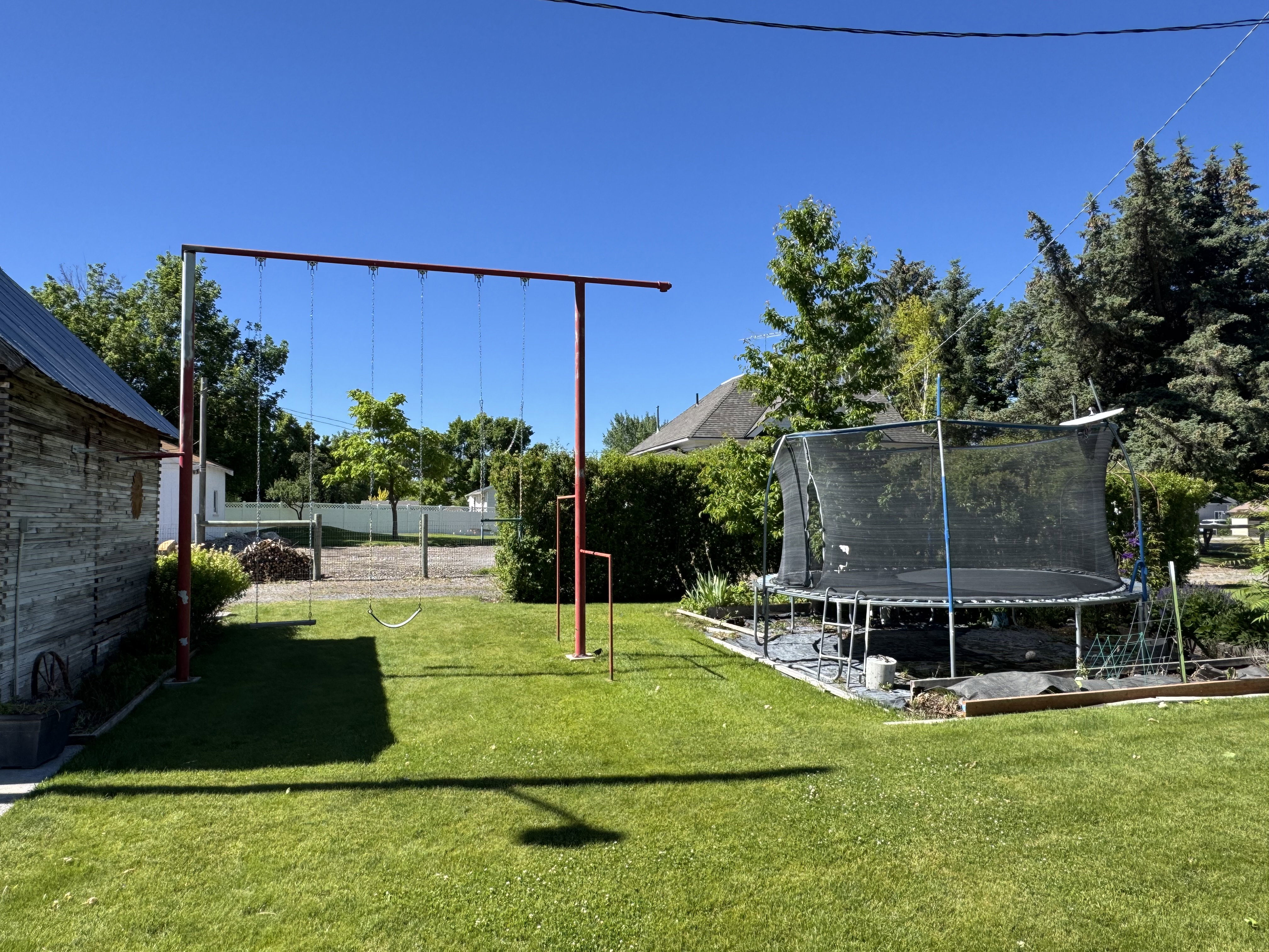 Expansive green lawn featuring mature trees and a swing set
