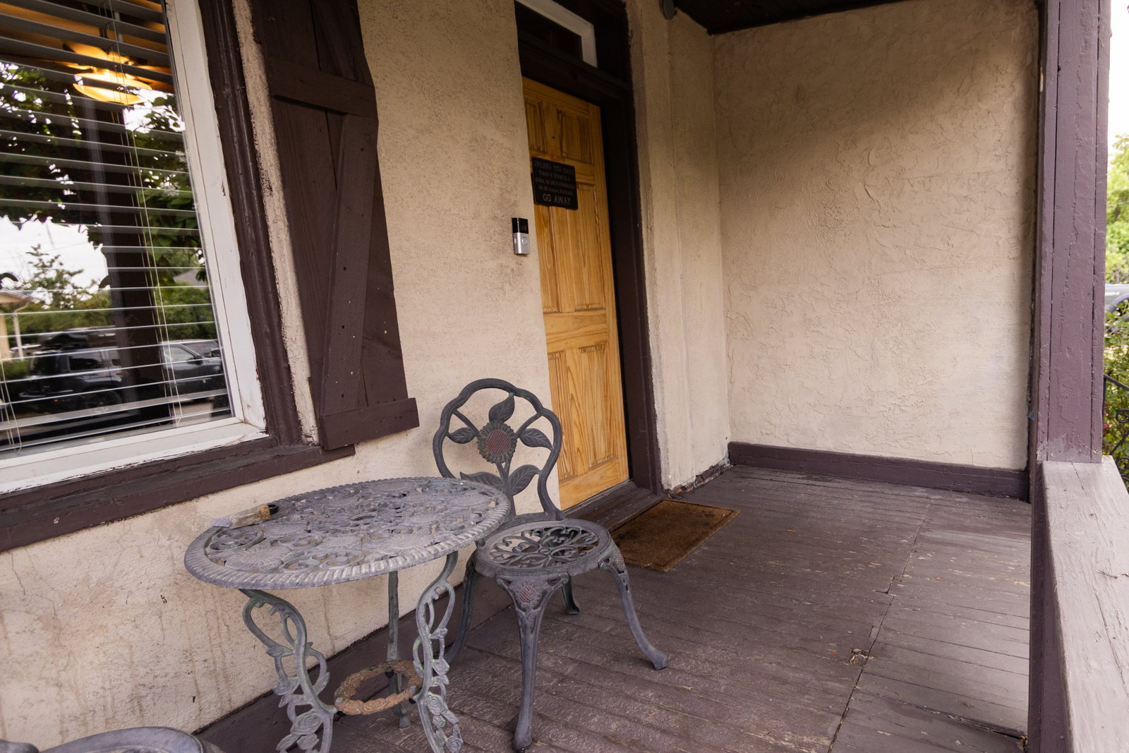 Front porch featuring a wood-paneled door, textured stucco exterior, and painted wood flooring