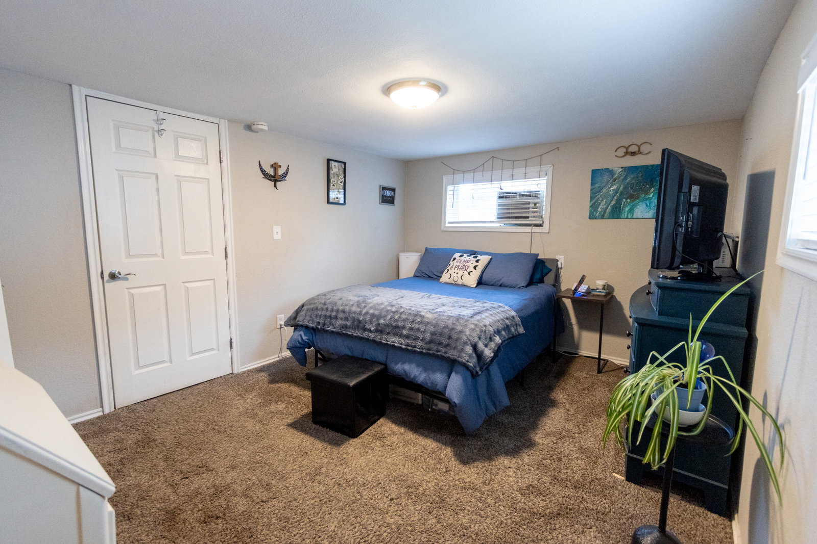 Carpeted room featuring light gray walls, a white paneled door, two windows with blinds, and a flush-mount ceiling light fixture