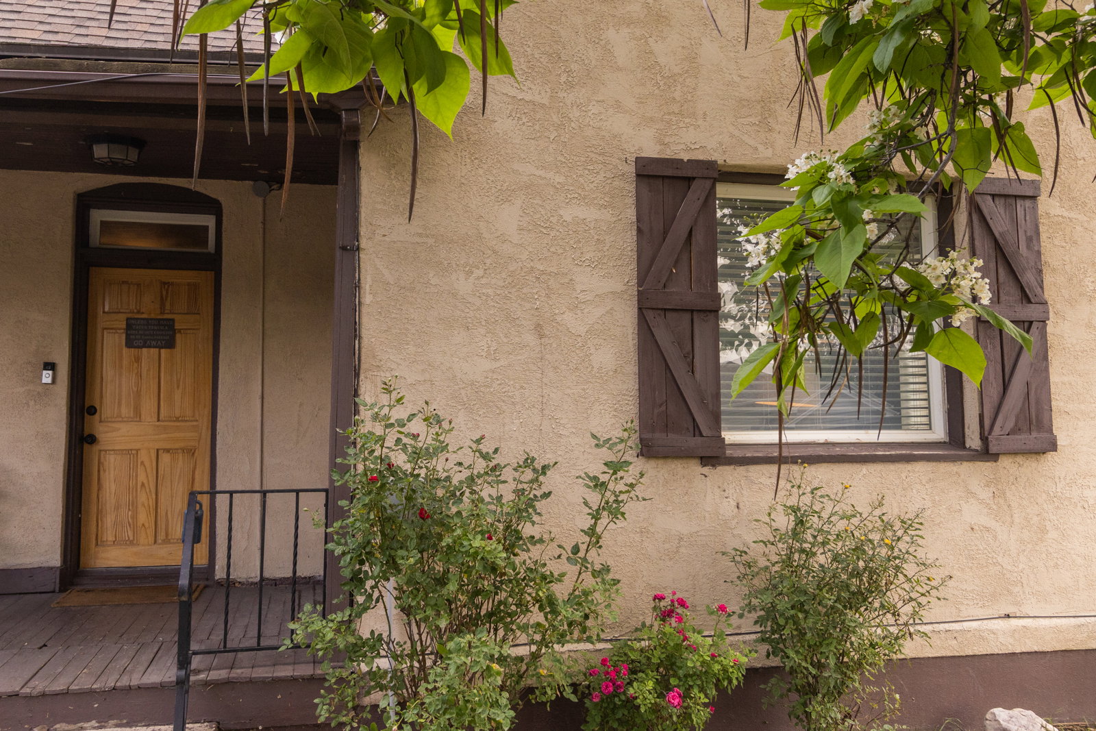 Stucco exterior with a natural wood-panel entry door, transom window, and dark trim