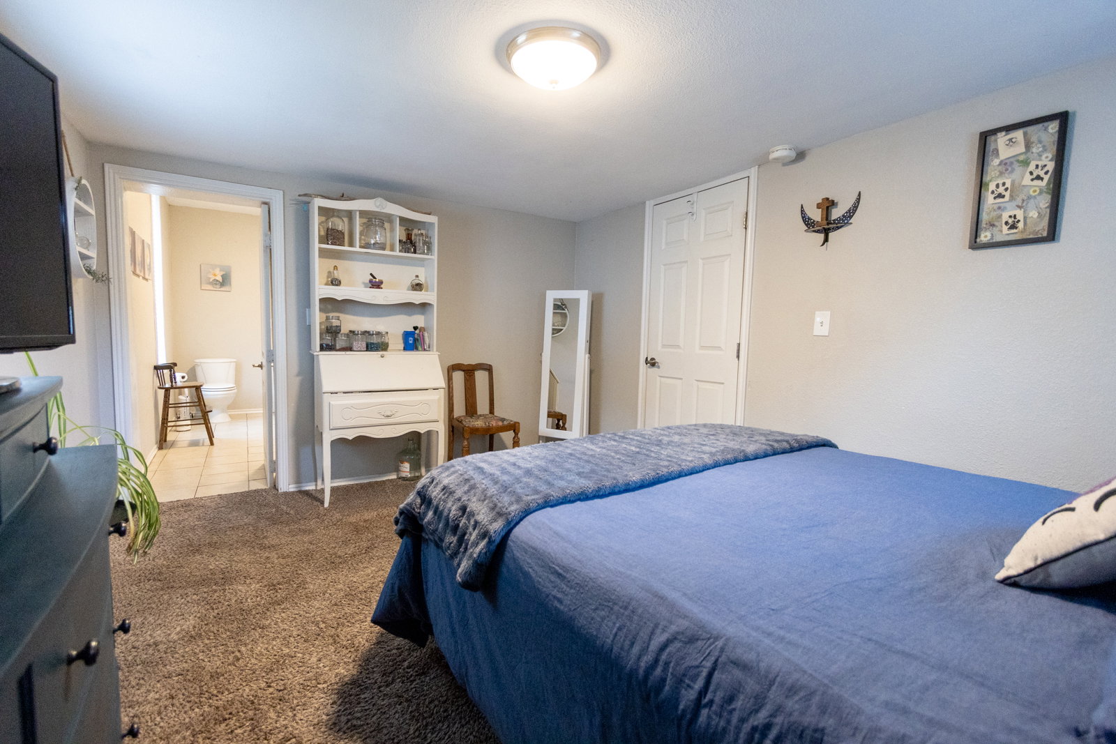 Carpeted bedroom featuring a flush-mount ceiling light, a built-in secretary desk with shelving, and an interior door