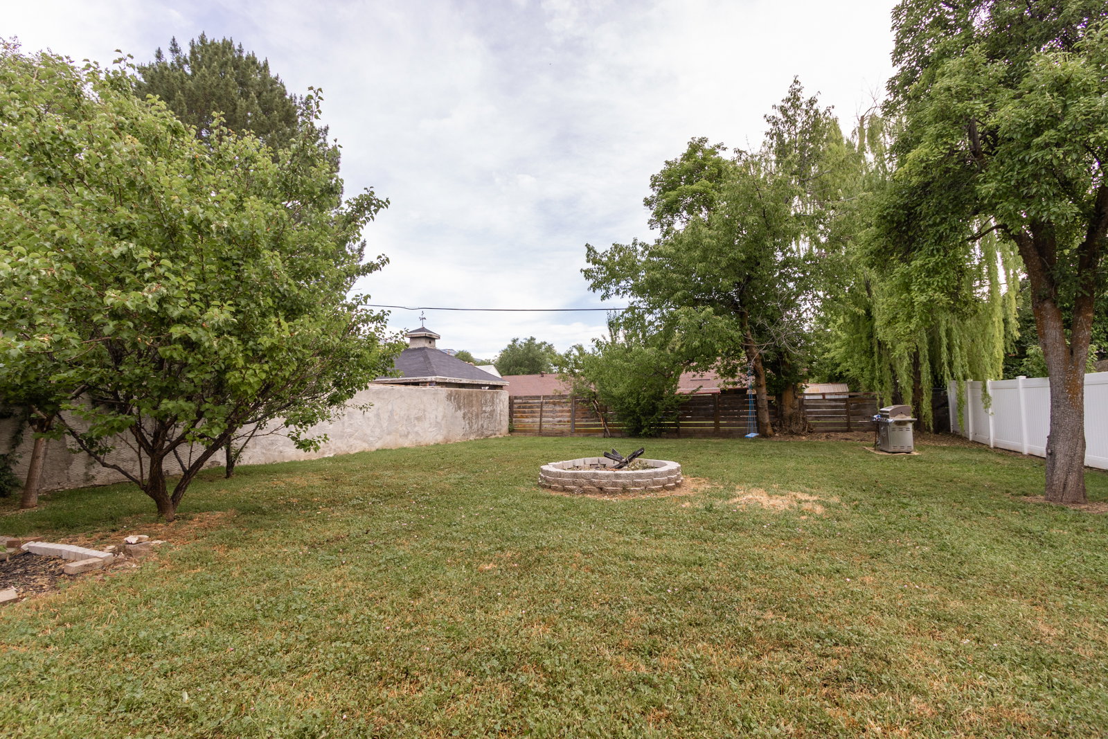 Spacious backyard featuring a built-in stone fire pit