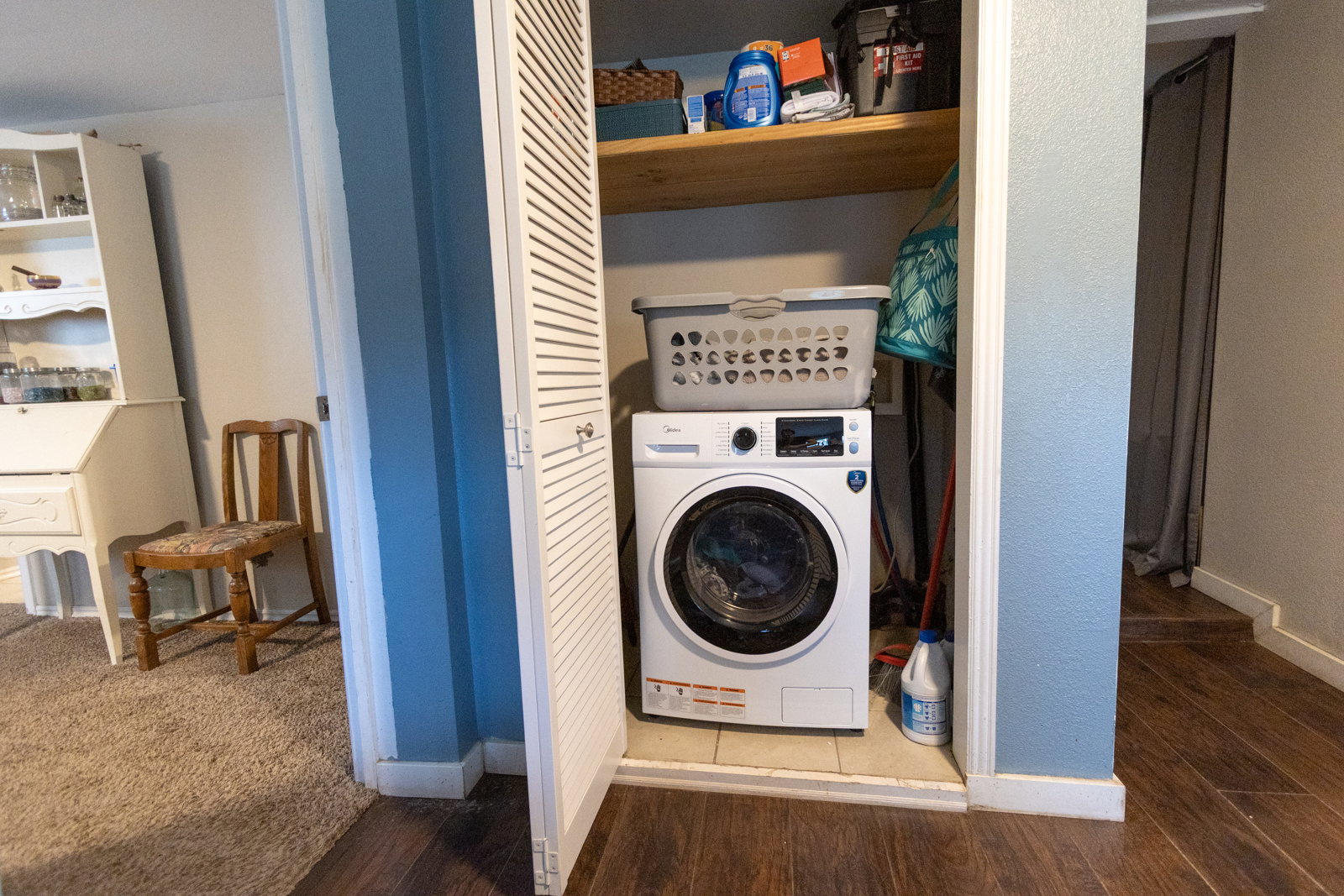 Dedicated laundry closet featuring a built-in shelf, tiled flooring, and louvered bifold doors