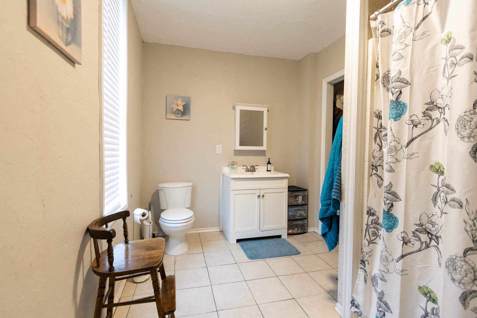 Bathroom featuring tile flooring, a white vanity with a single sink, a wall-mounted medicine cabinet, a toilet, and a window with blinds