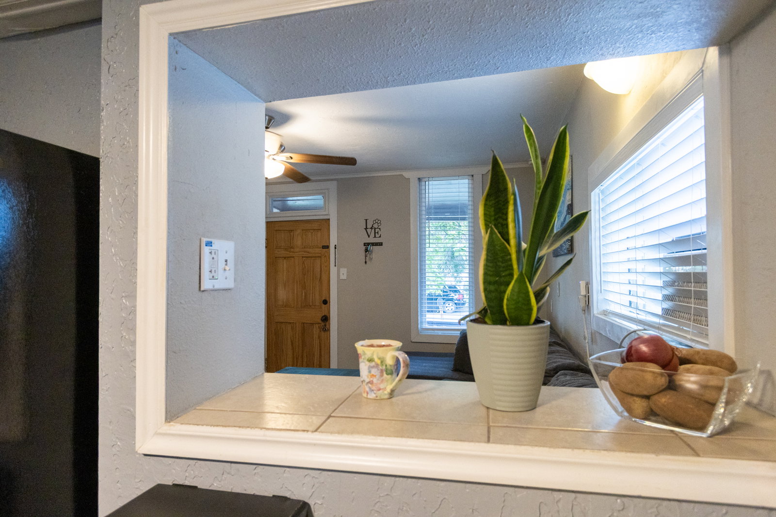 Pass-through window with white trim and a tiled sill, offering a view into an adjacent living space