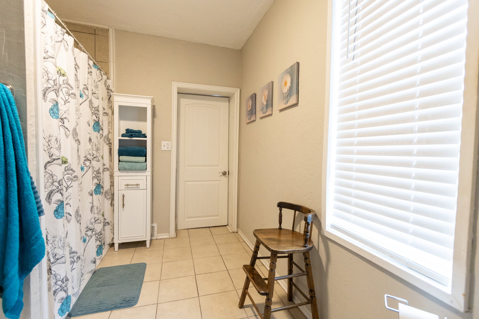 Bathroom featuring a shower with tiled surround, light tan wall paint, tiled flooring, and a window with white blinds