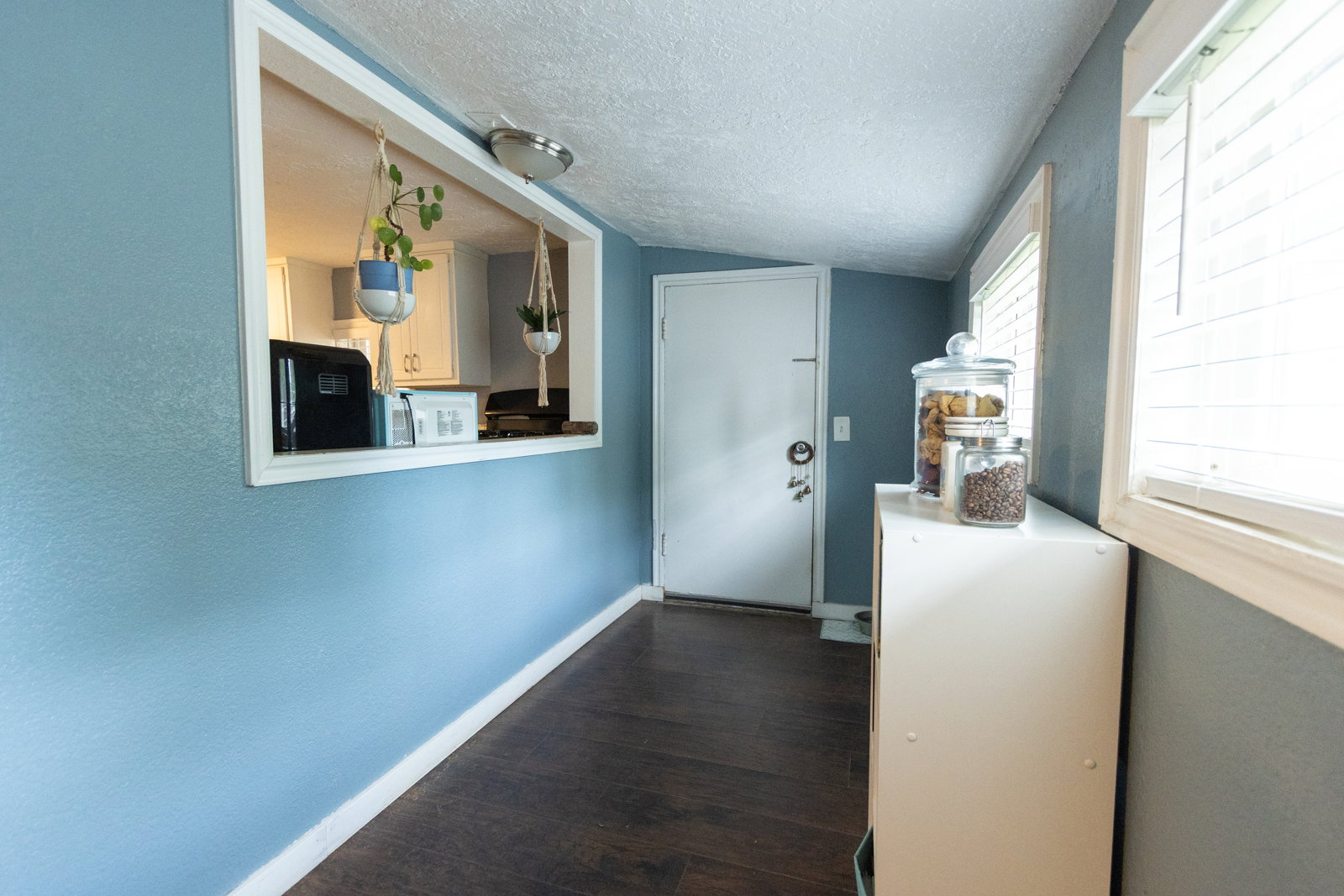 Entryway featuring dark wood-finish flooring, light blue walls, and white trim