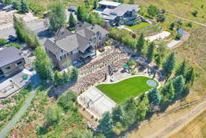 Expansive terraced yard featuring a pickleball court, artificial turf lawn with in-ground trampoline, and a playground structure