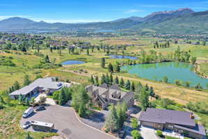 Expansive property featuring multiple architectural styles, a paved drive, mature evergreen landscaping, and surrounding mountainous terrain