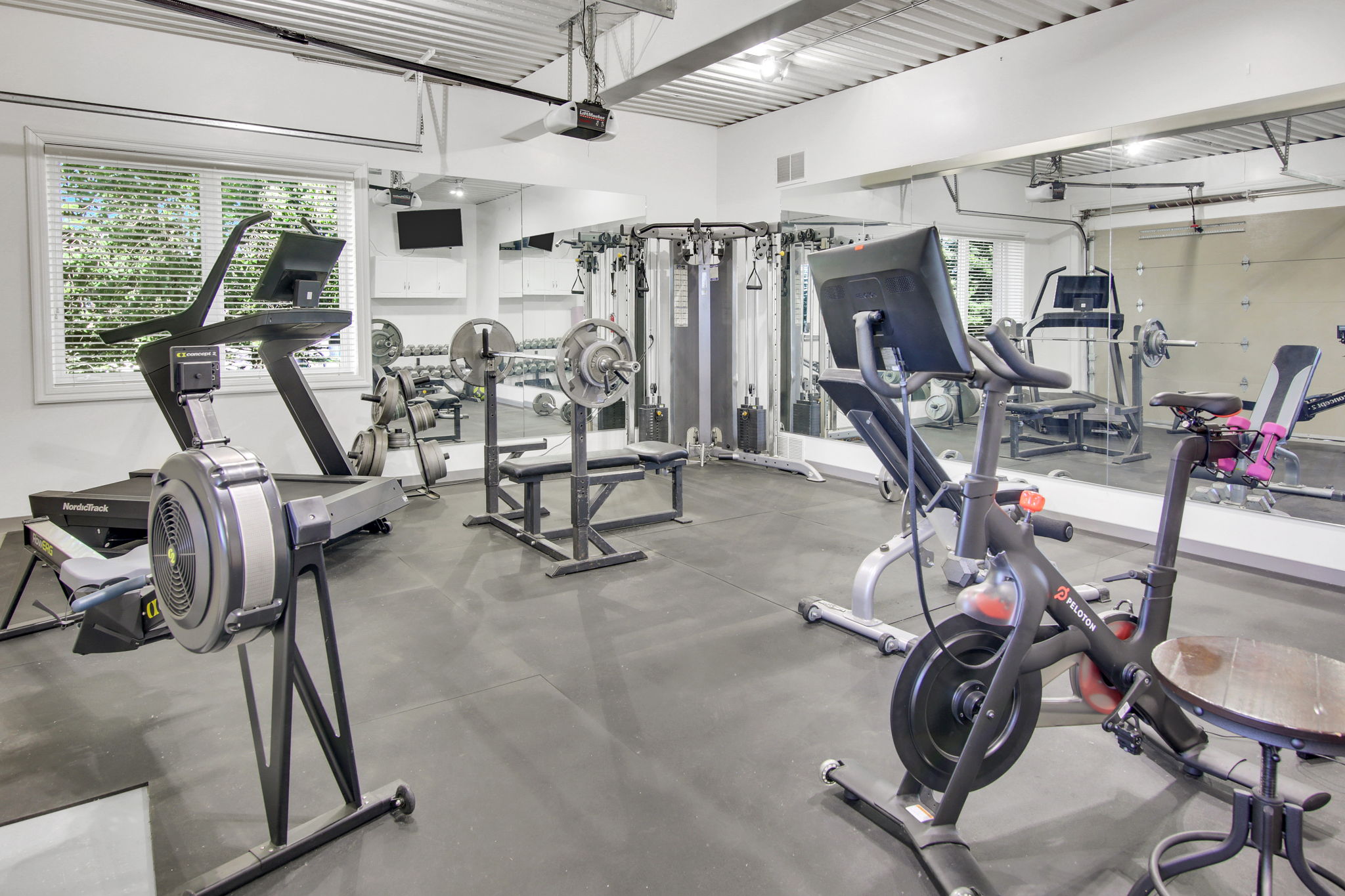 Dedicated fitness area featuring durable rubber flooring, expansive wall-mounted mirrors, and a white corrugated ceiling