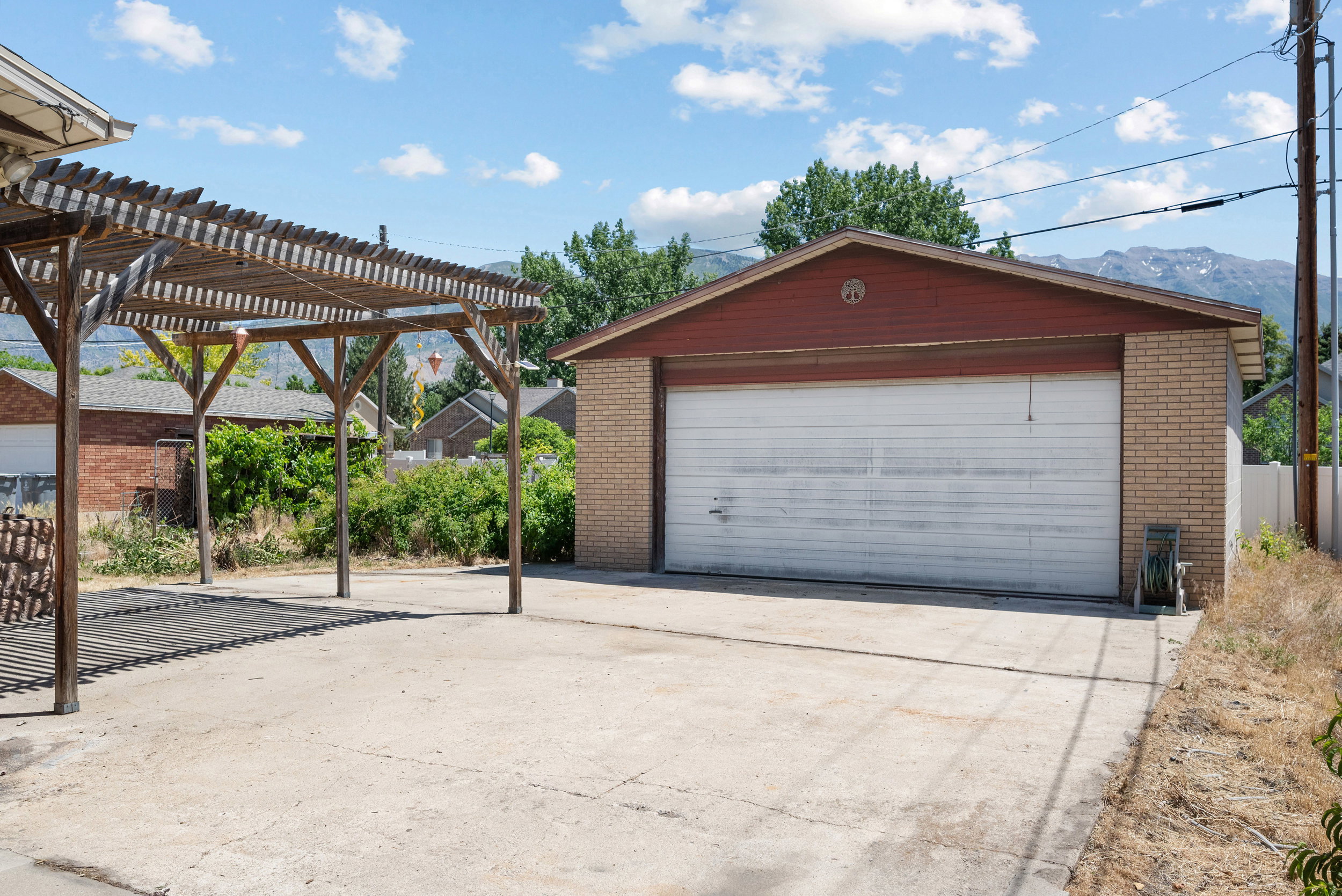 Detached garage with light brick siding and a red gable roof