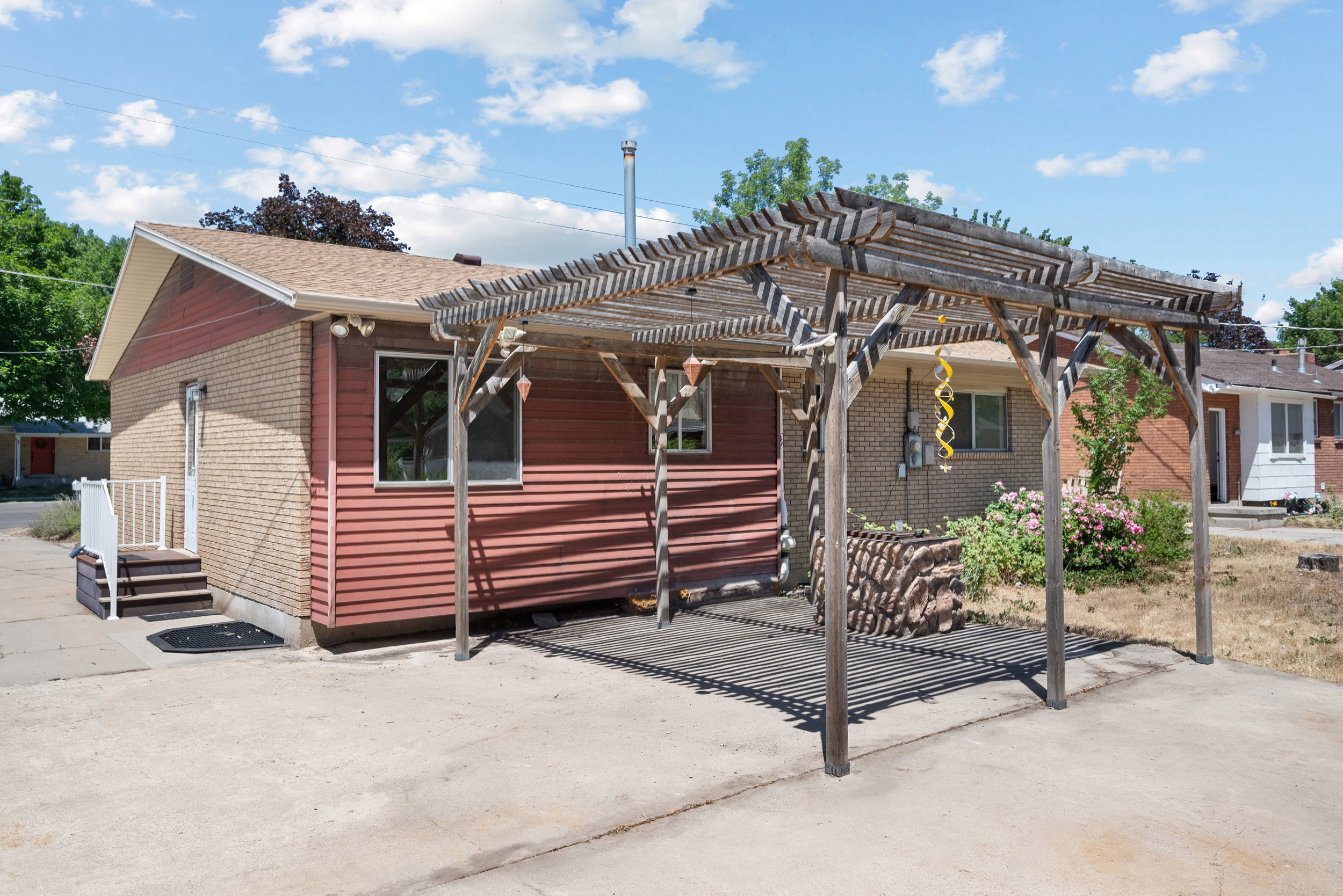 Exterior featuring brick and horizontal siding, a gabled roofline, a wooden pergola, and a concrete patio