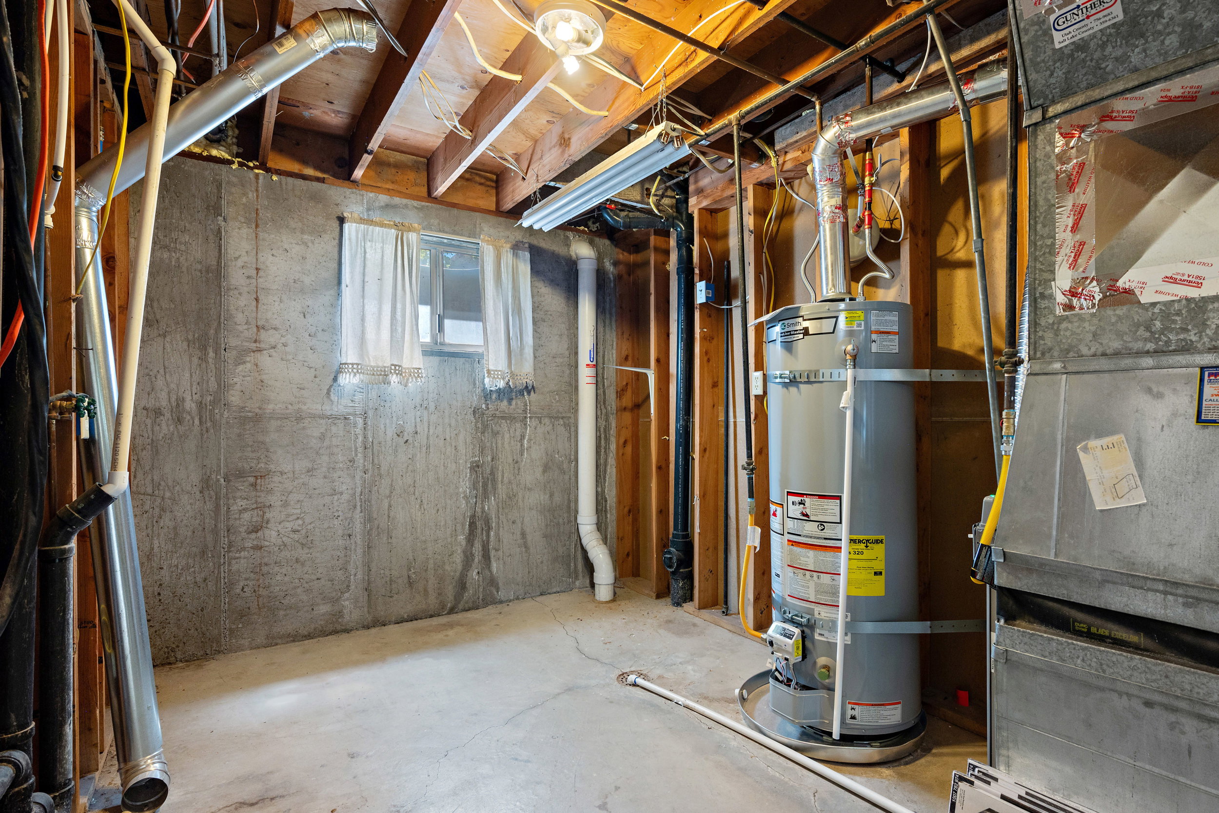 Utility space featuring a water heater and furnace unit
