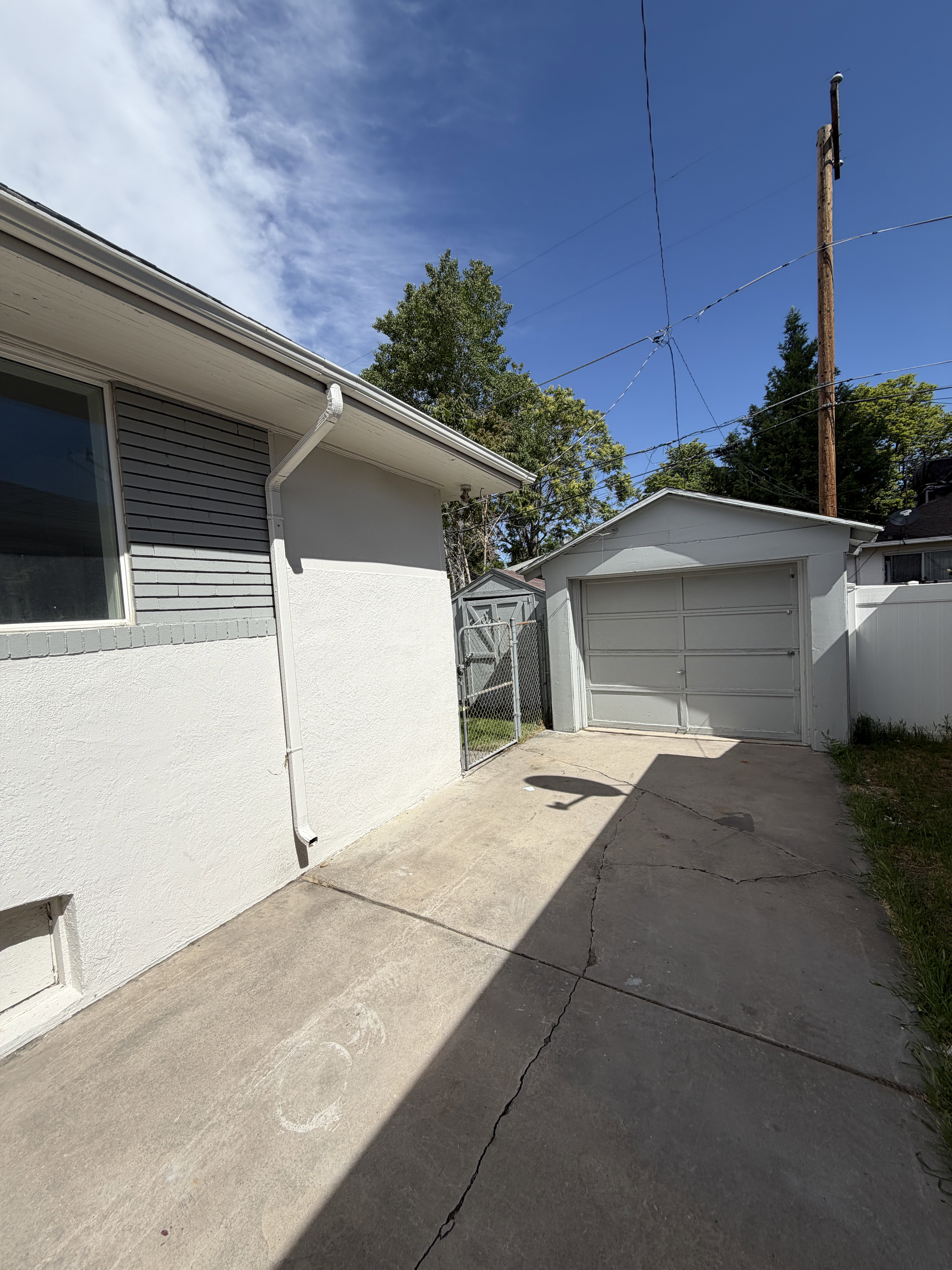 Detached garage with a paneled door, a concrete driveway, and a chain-link fence