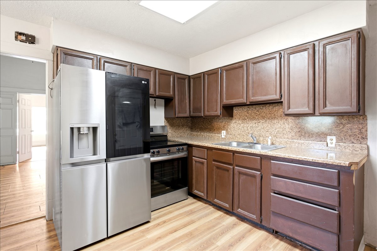 Kitchen featuring wood-finish flooring, dark wood cabinetry, a stainless steel refrigerator, and a stainless steel range with a built-in oven