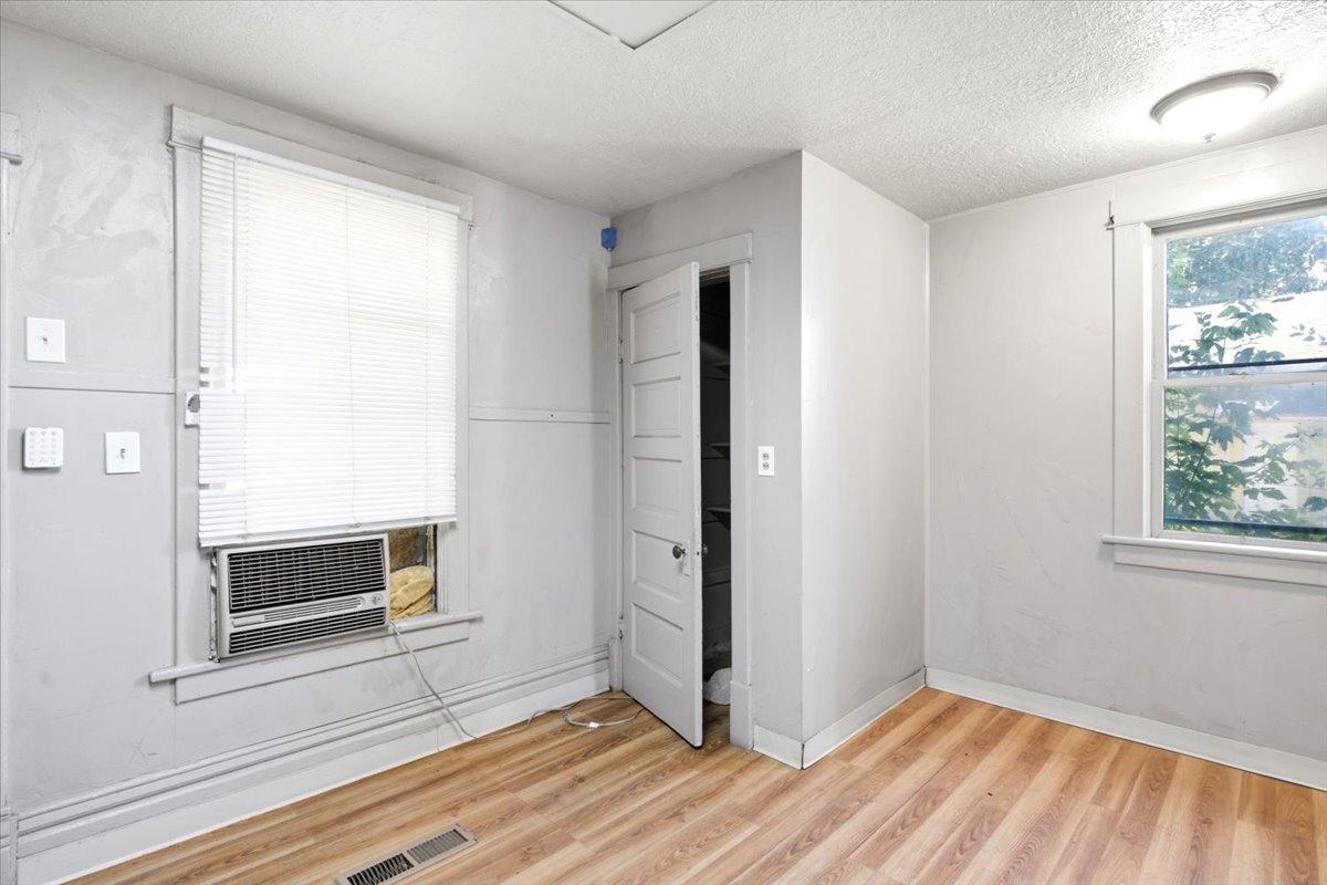 Room featuring wood-finish flooring, two windows with white trim, and a built-in closet with a paneled door