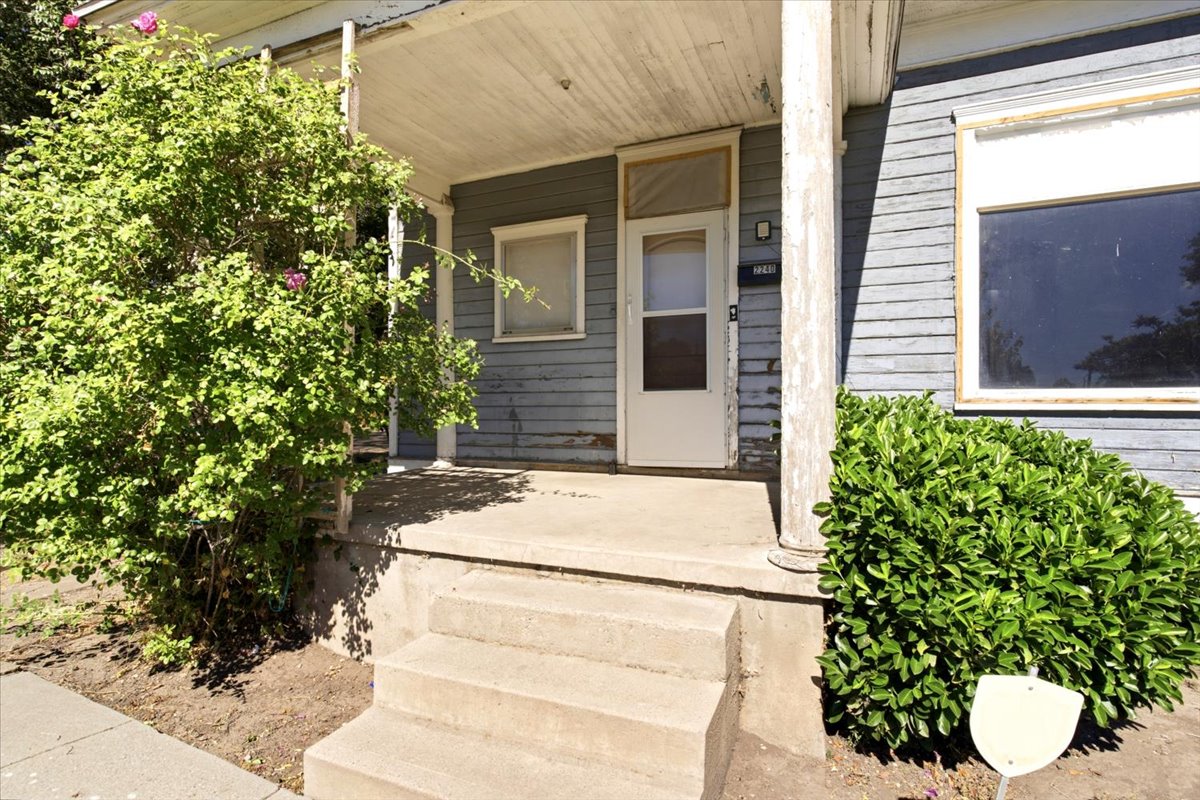 Exterior featuring horizontal siding, a concrete porch with steps, and mature shrubs