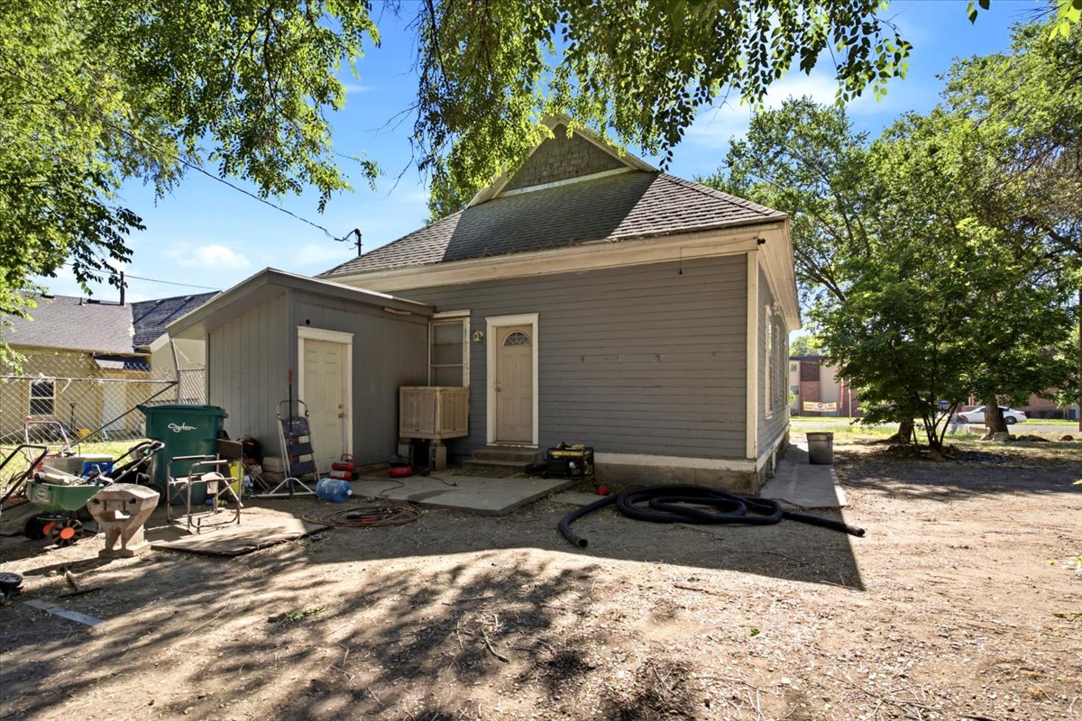 Rear exterior featuring gray siding, a gabled roof, and two access doors