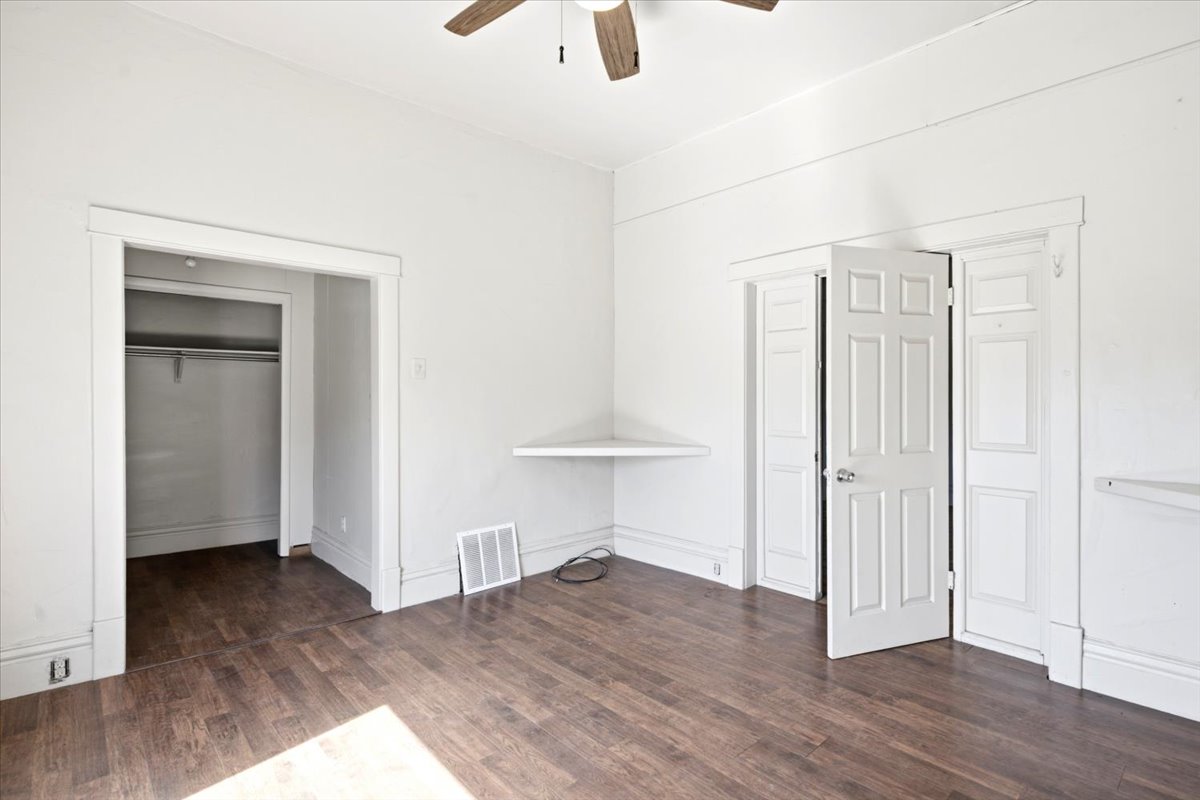 Spacious room featuring wood-finish flooring, a built-in corner desk, and a ceiling fan