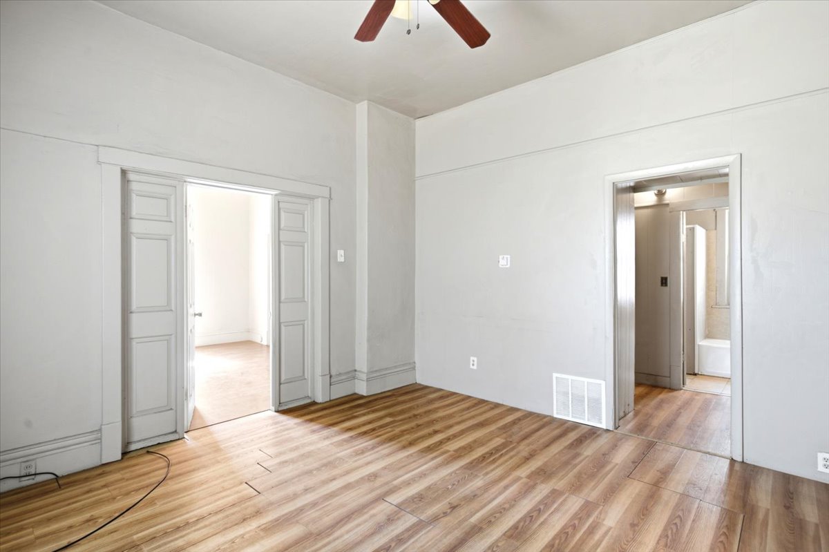 Spacious interior room featuring wood-finish flooring, light gray walls, and white ceiling