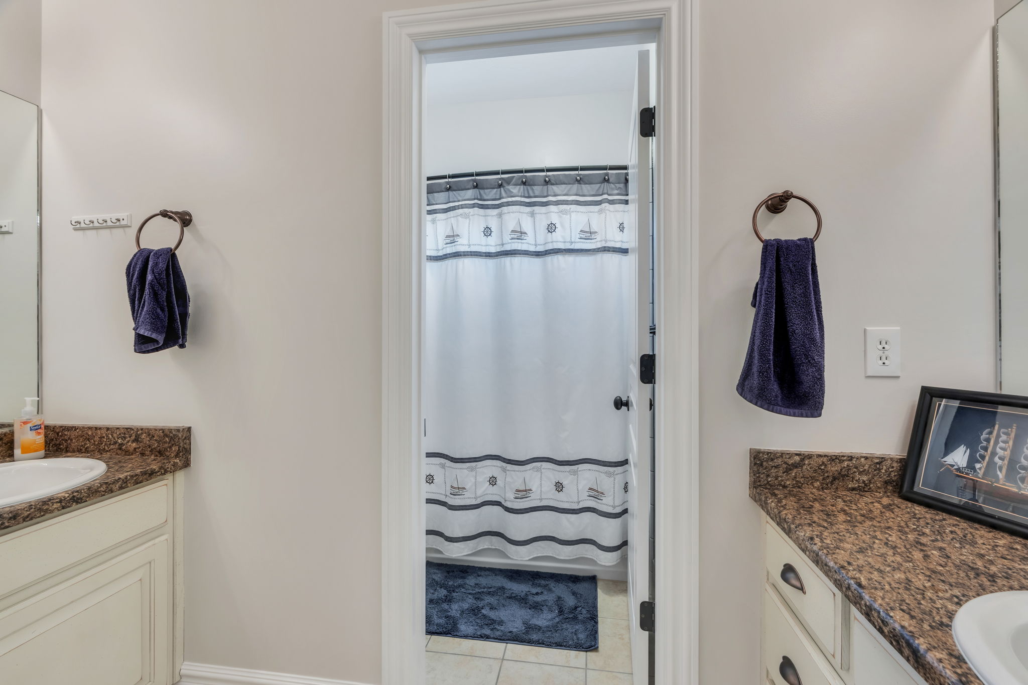 Bathroom featuring dual vanity areas with granite-style countertops and undermount sinks