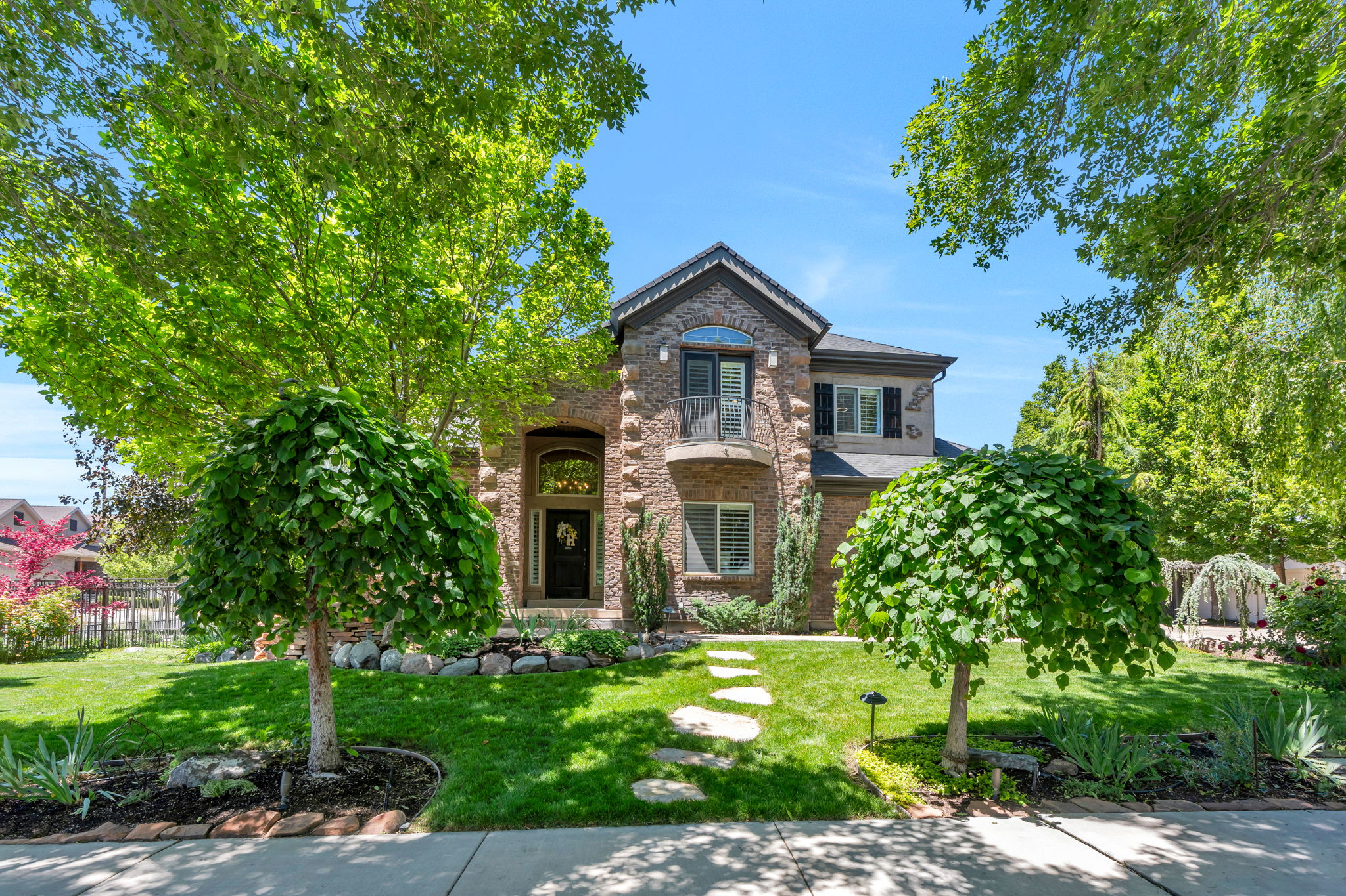 Two-story brick exterior featuring a front balcony and arched entryway
