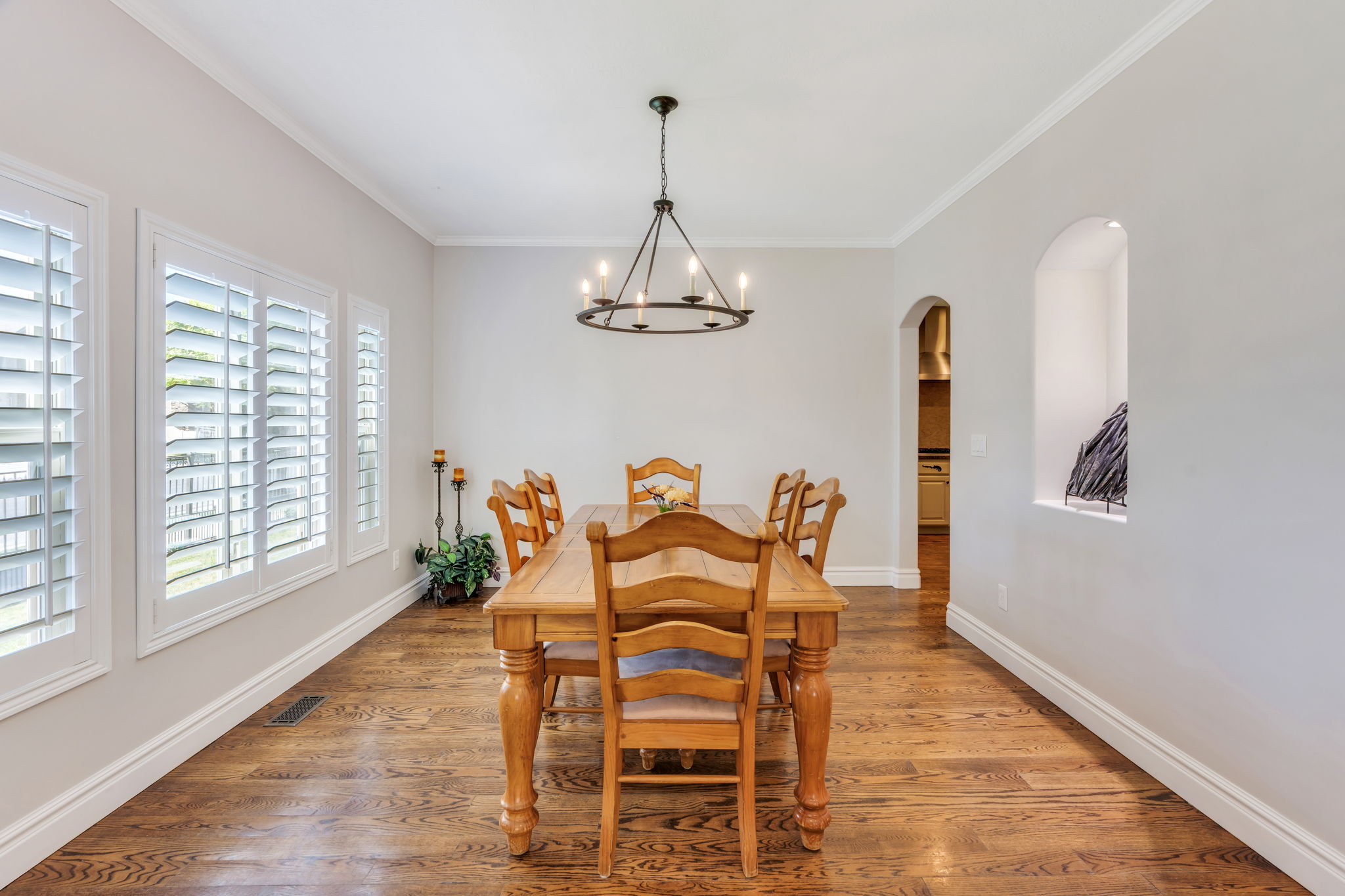 Dining space featuring wood-finish flooring, white crown molding, and plantation shutters