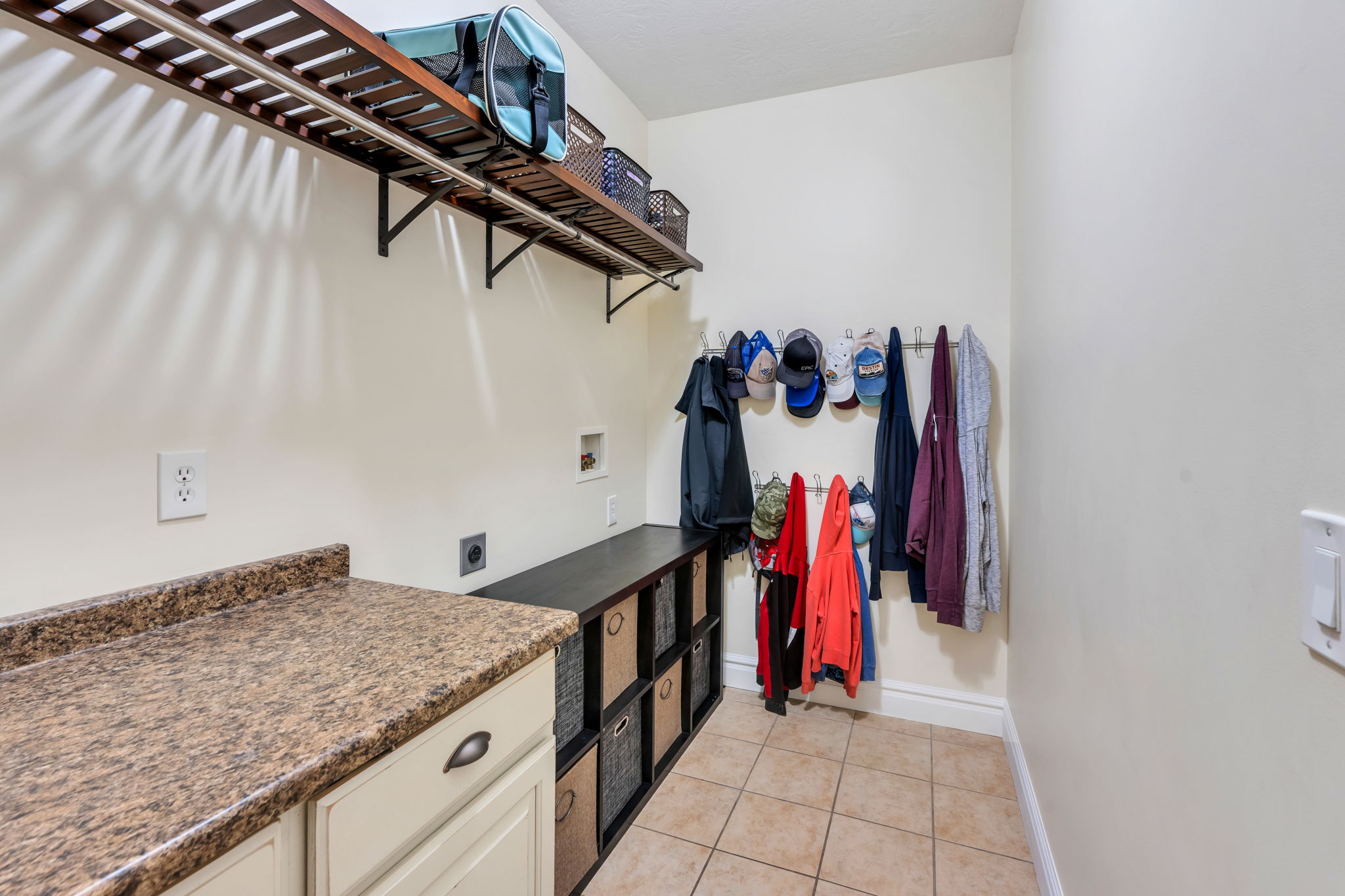Laundry room featuring tiled flooring, built-in shelving, stone-finish countertops, and a utility sink hookup