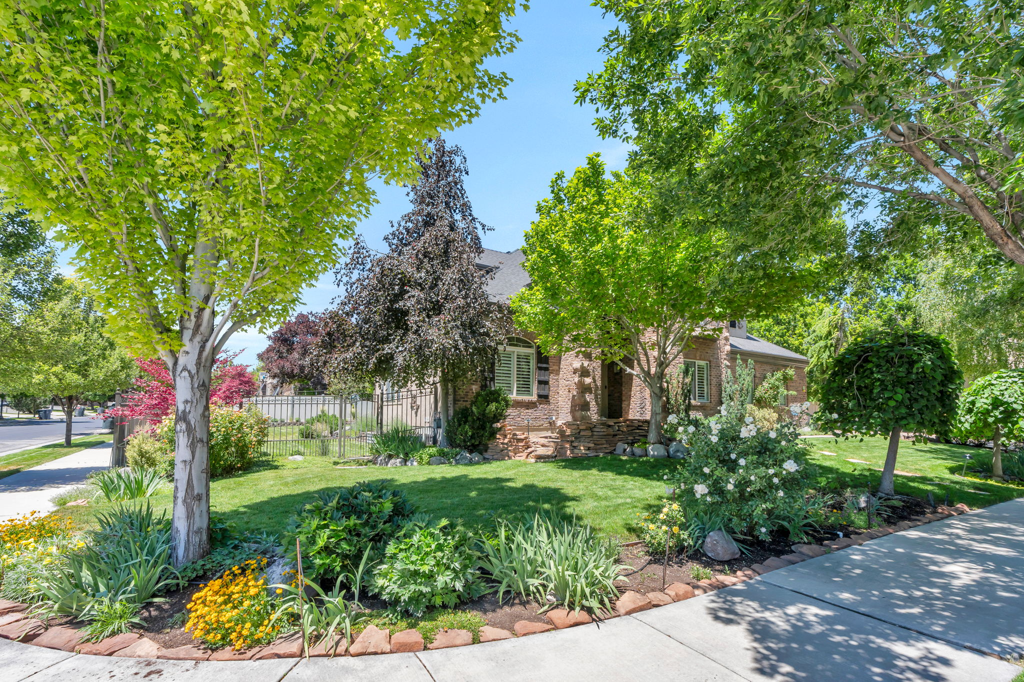 Lush, mature landscaping with a verdant lawn frames the brick and stone exterior