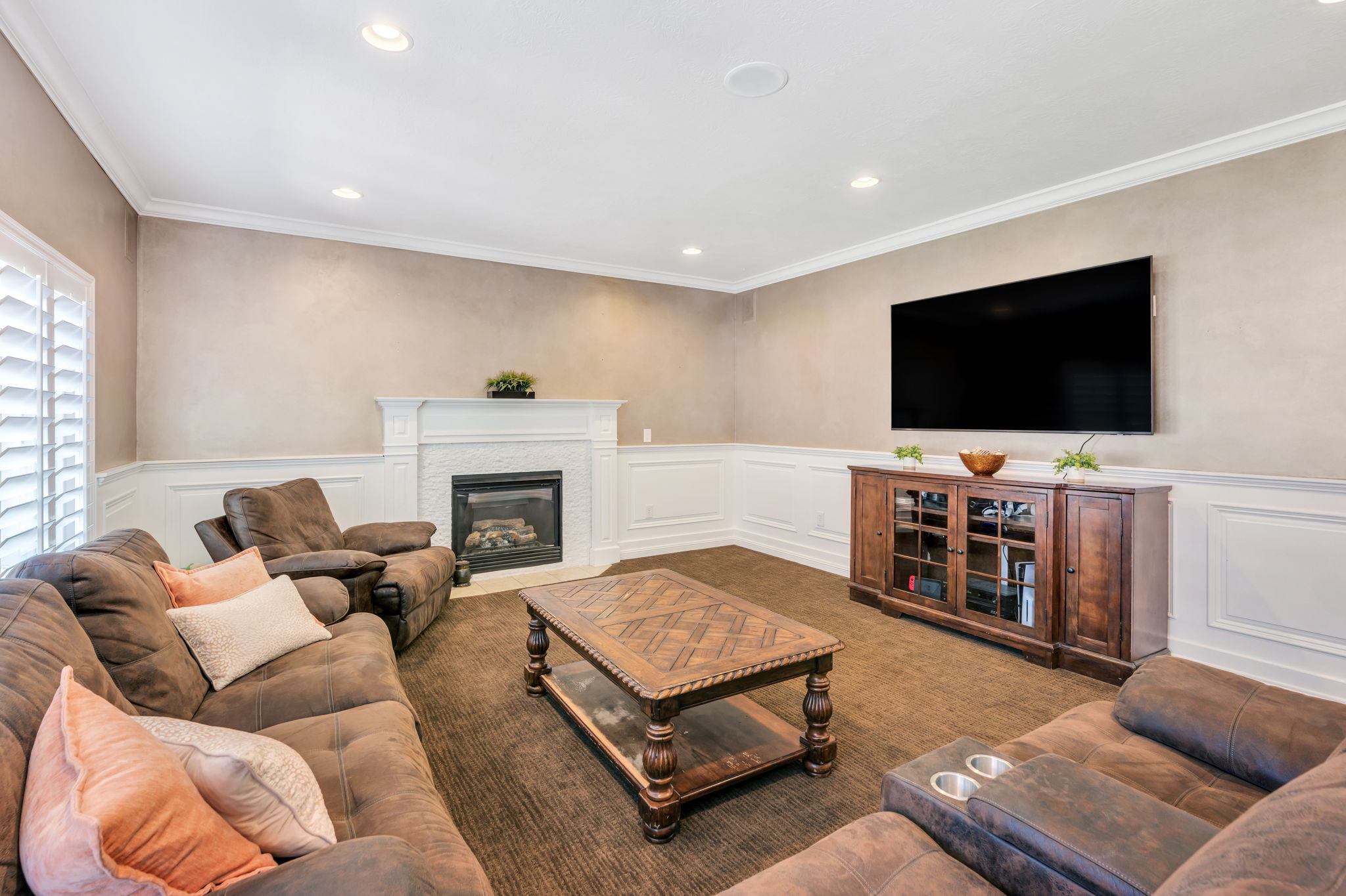 Living space featuring a fireplace with a detailed white mantel, white wainscoting, recessed lighting, and crown molding