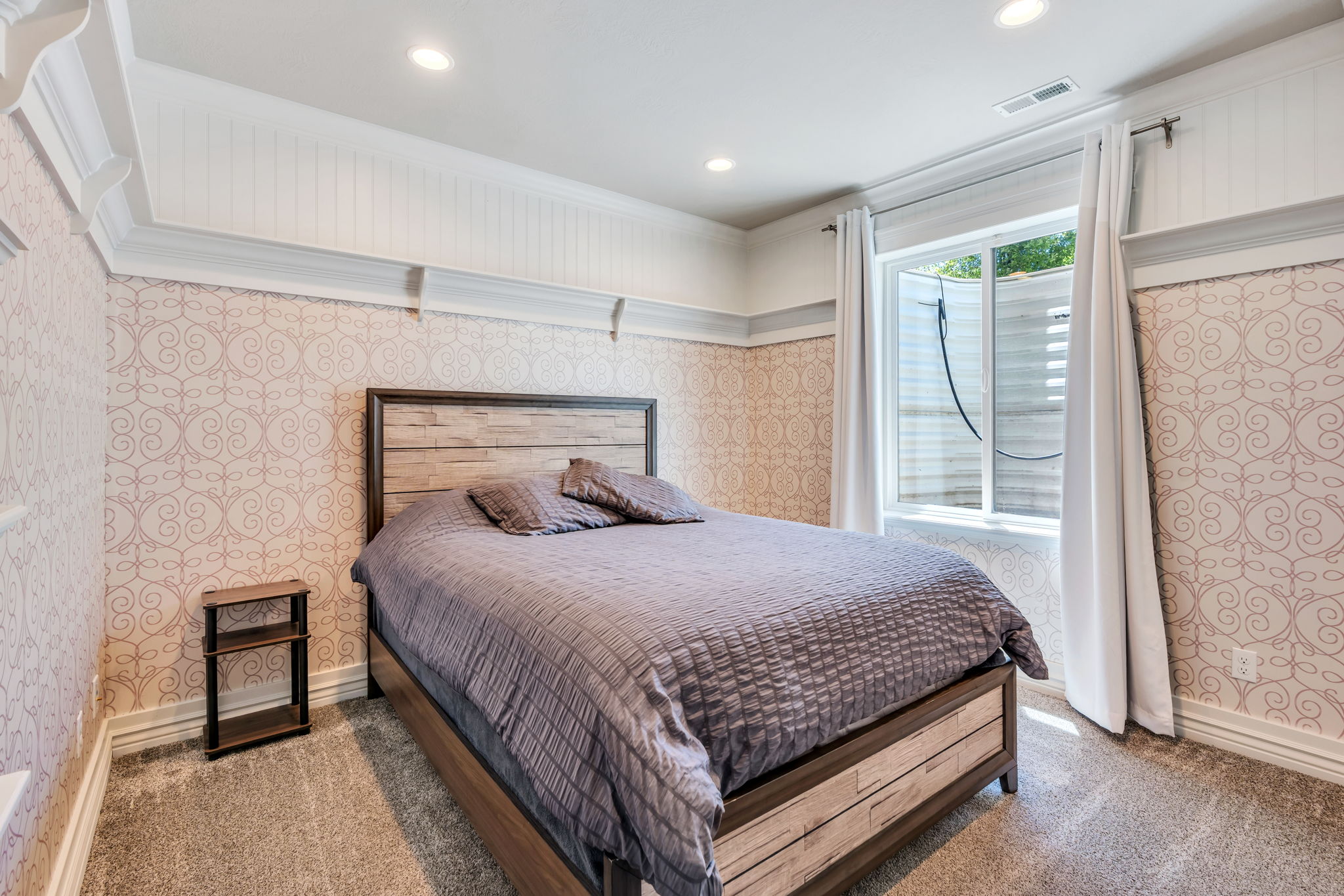 Carpeted room featuring patterned wallpaper and white wainscoting