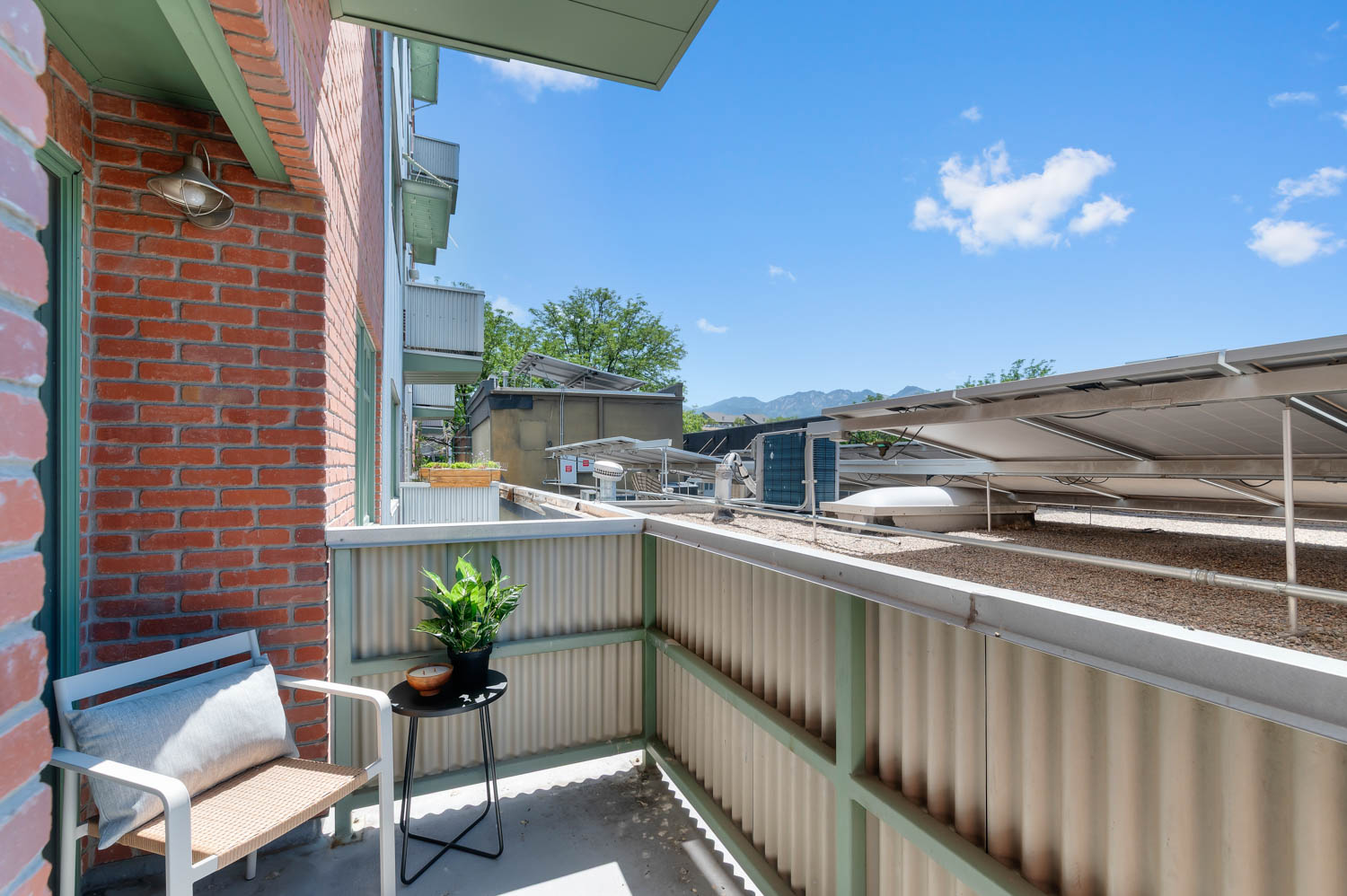 Private balcony with brick exterior and corrugated metal railing