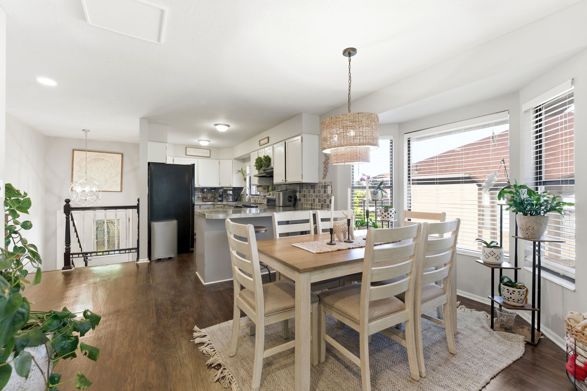 Dining area featuring wood-finish flooring, a woven pendant light fixture, and a bay window