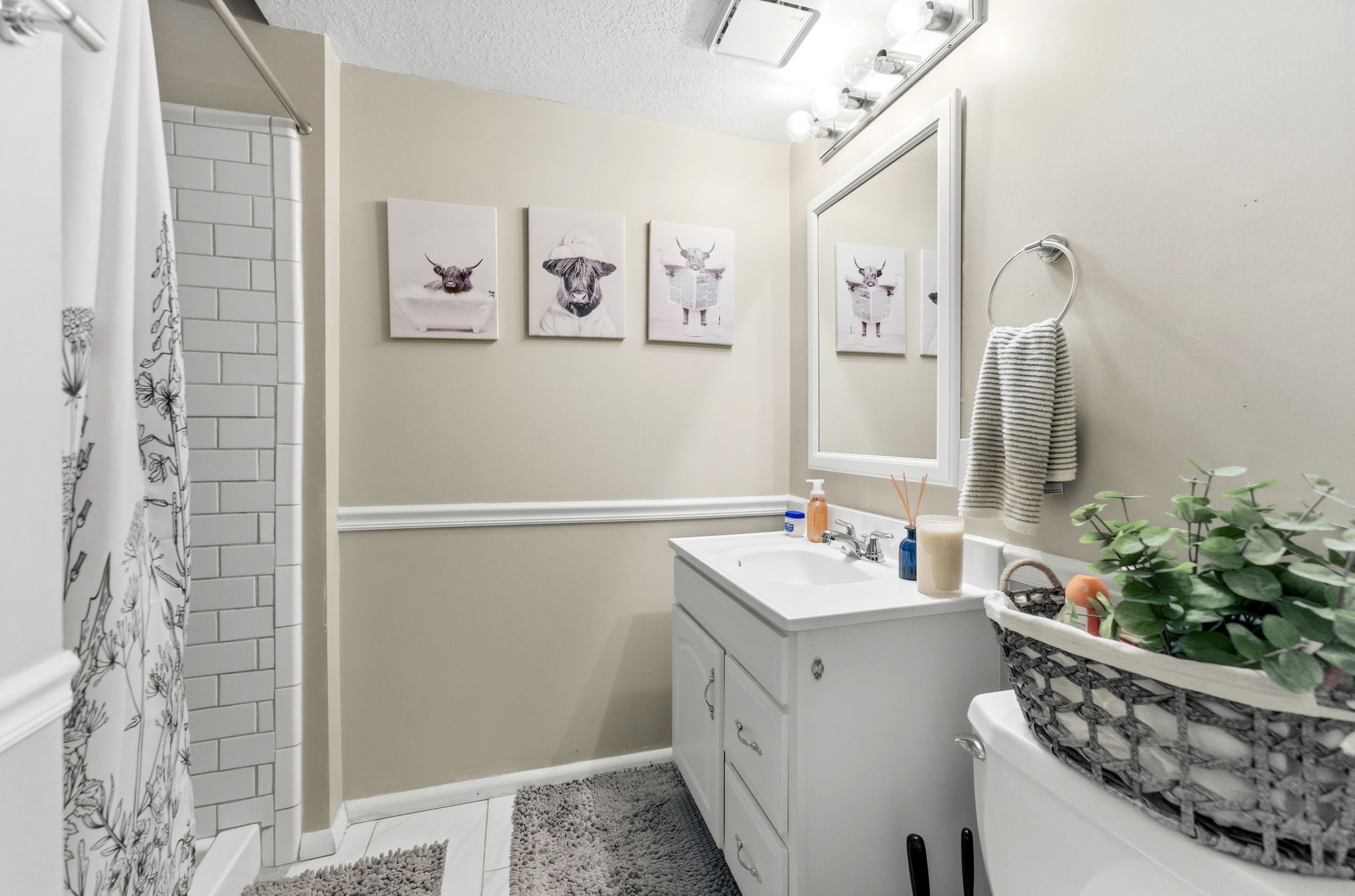 Bathroom featuring a single vanity with a white countertop and integrated sink, a white framed mirror, and a vanity light bar
