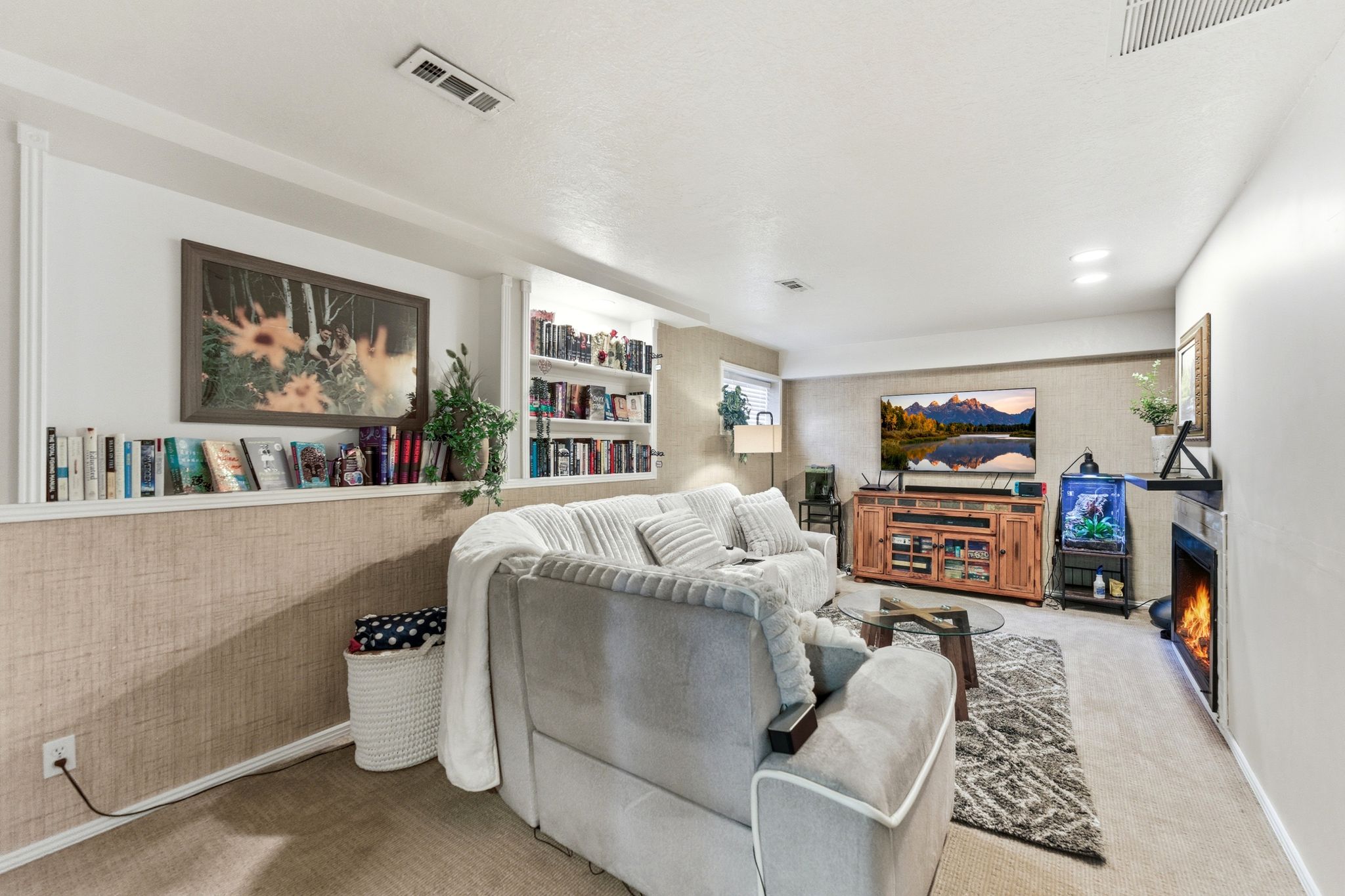 Finished living area featuring built-in shelving, a fireplace, and neutral carpeting