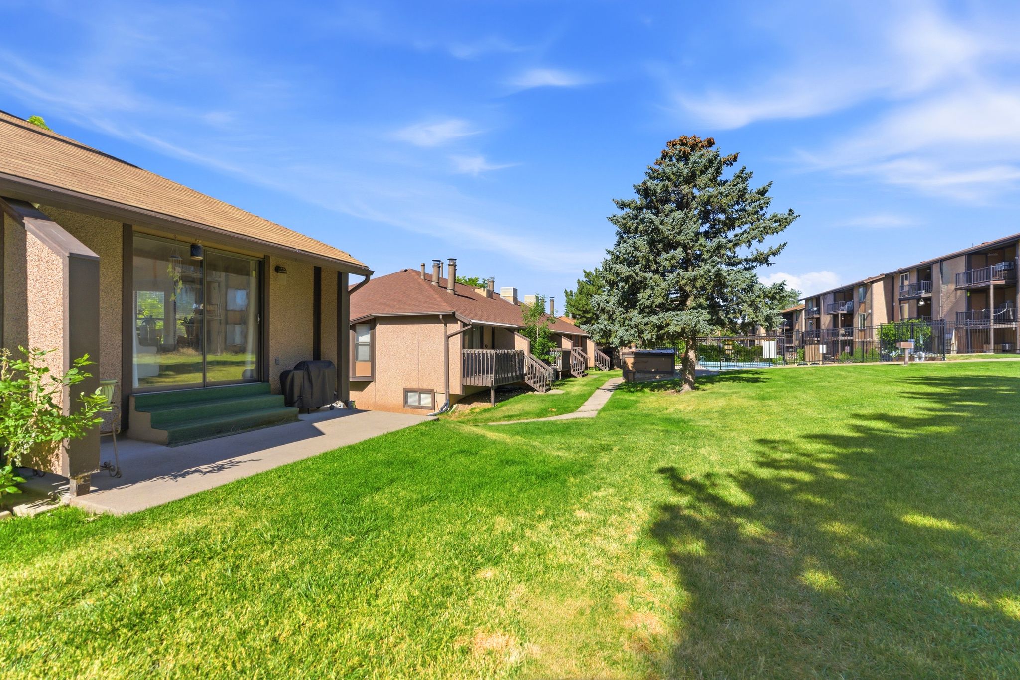 Expansive green lawn surrounded by mature trees and residential structures