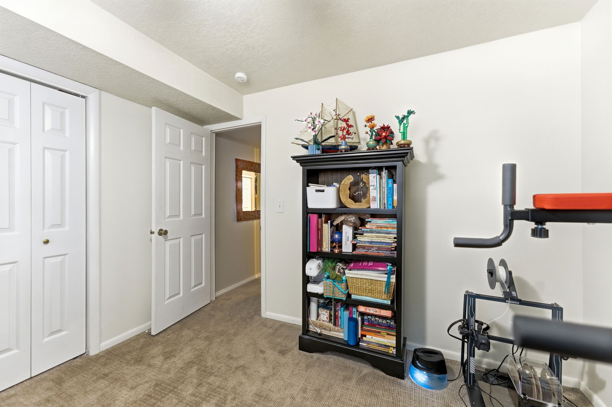 Carpeted room featuring a white paneled door, bi-fold closet doors with brass knobs, and a visible ceiling beam