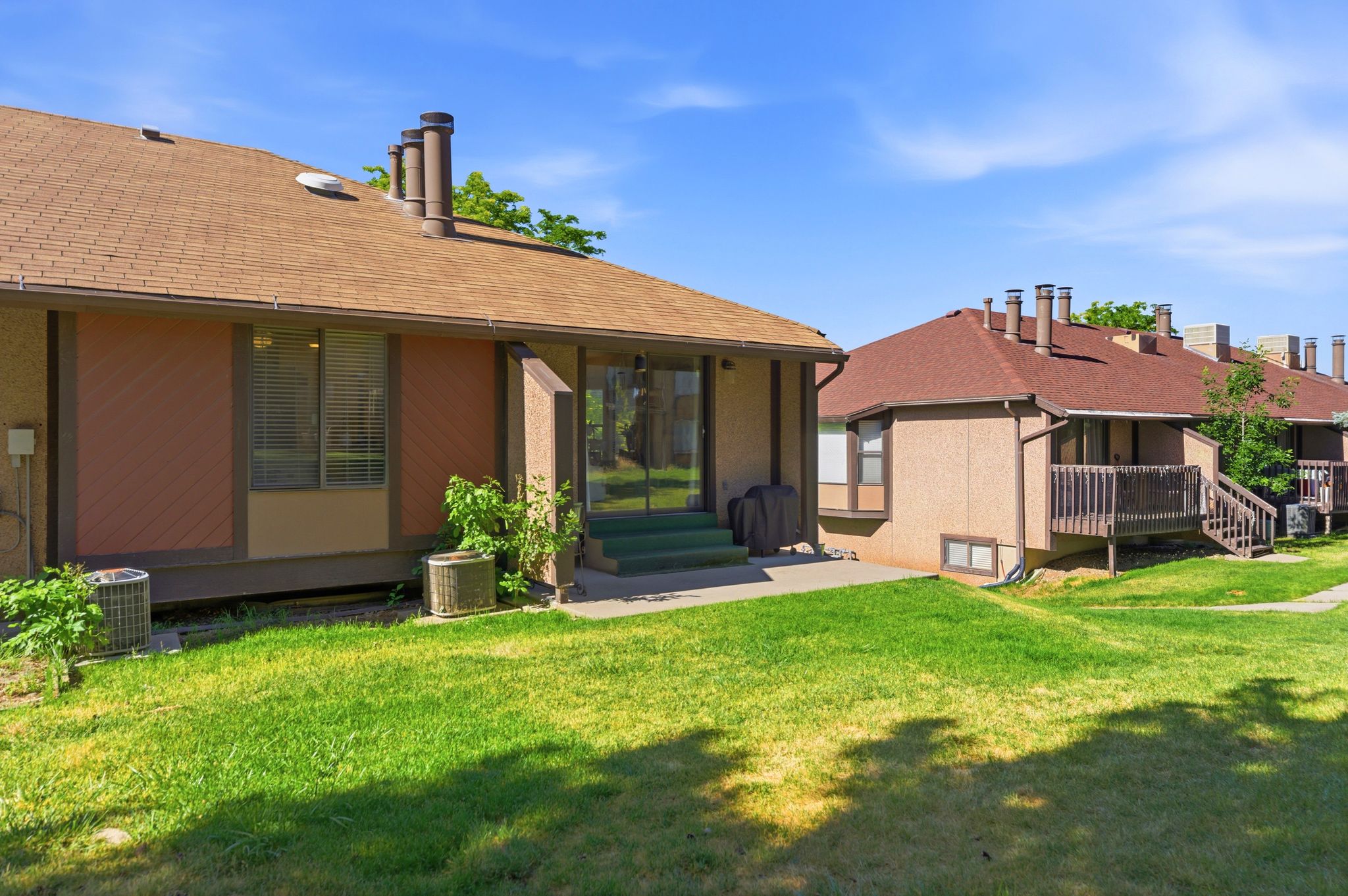 Rear exterior featuring a brown shingle roof, sliding glass patio door, and a concrete patio