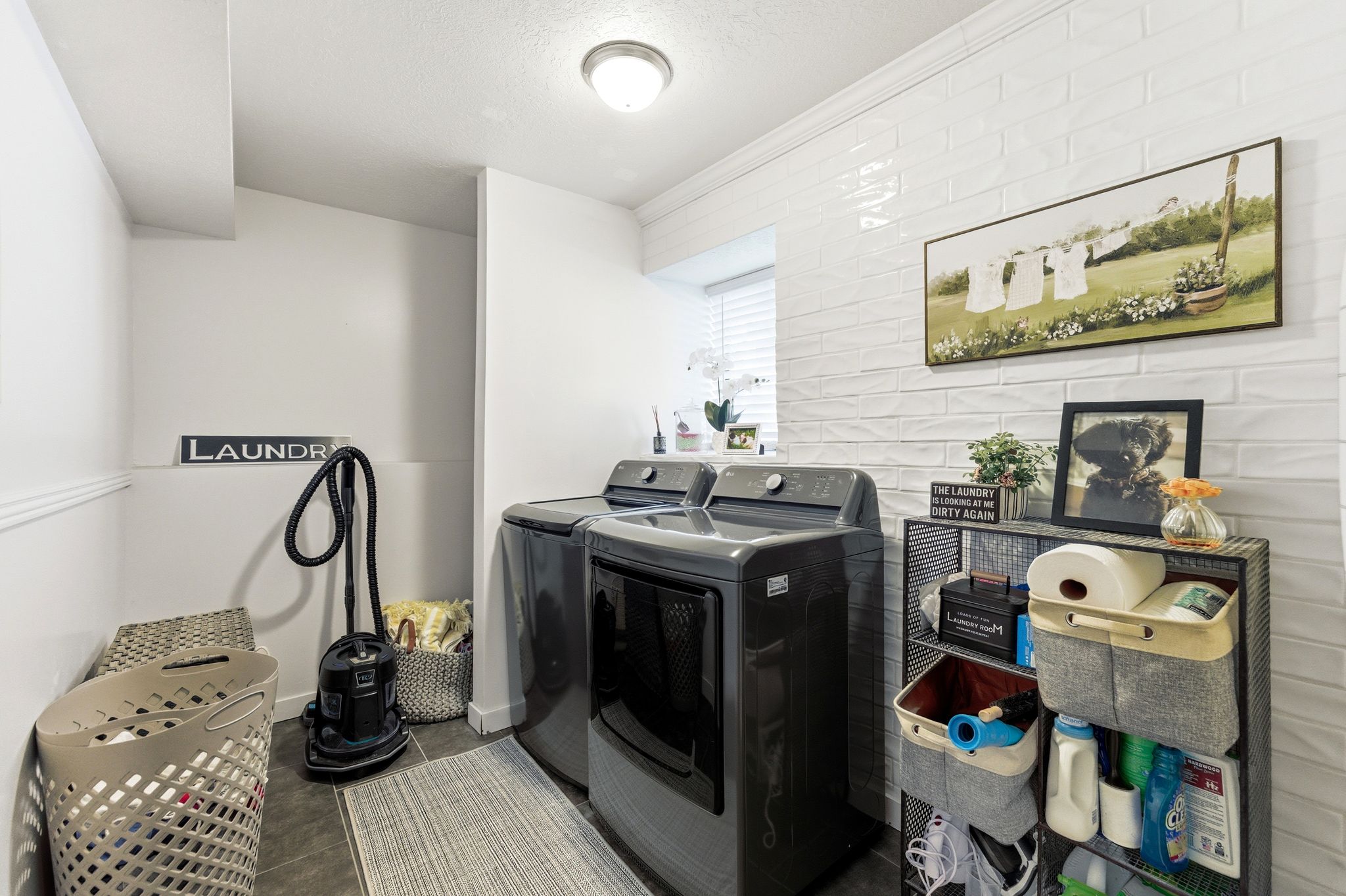 Dedicated laundry area featuring a tile floor, white painted walls, and a window with blinds