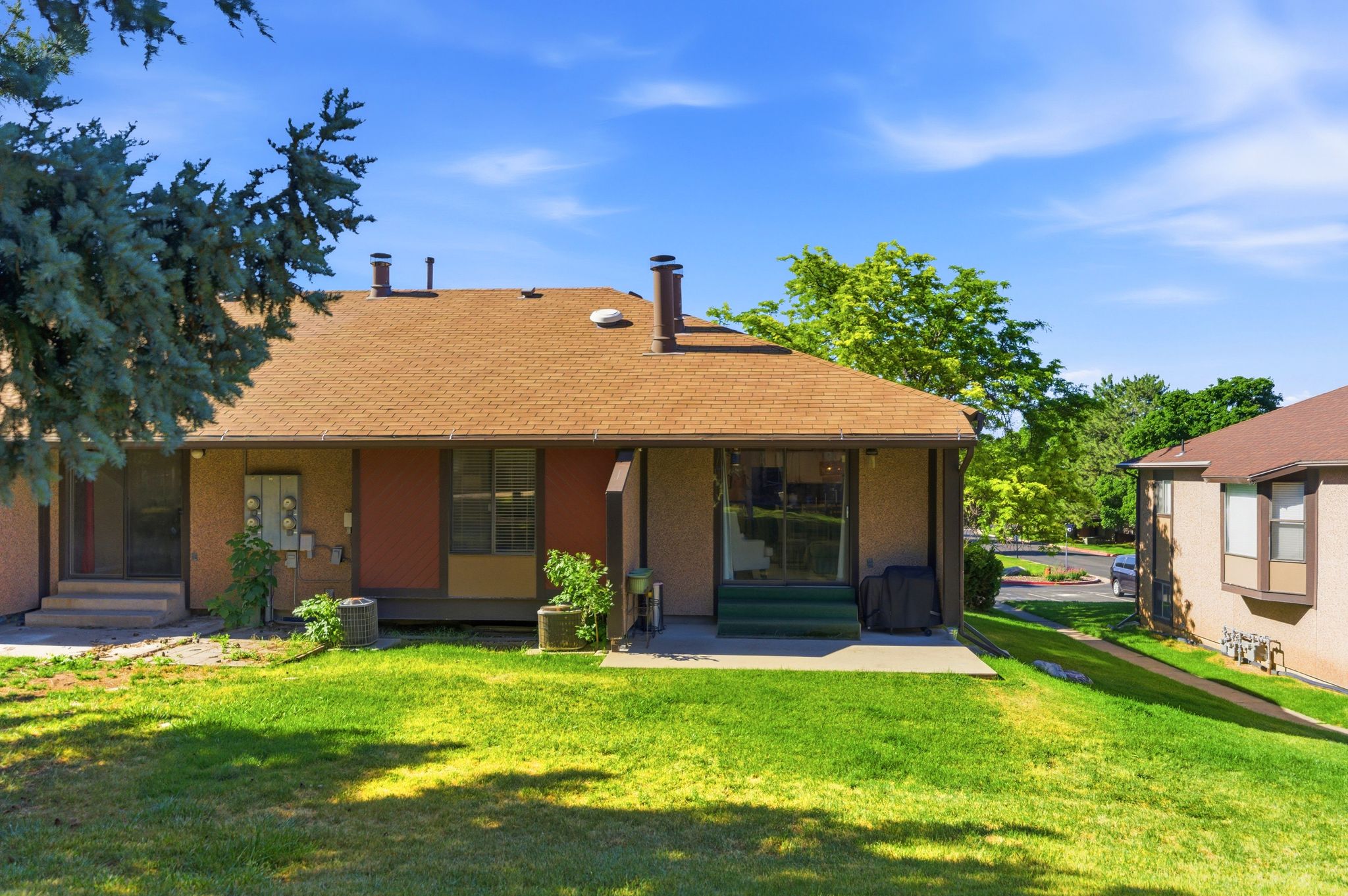 Expansive green lawn backing a multi-unit property with a shingle roof